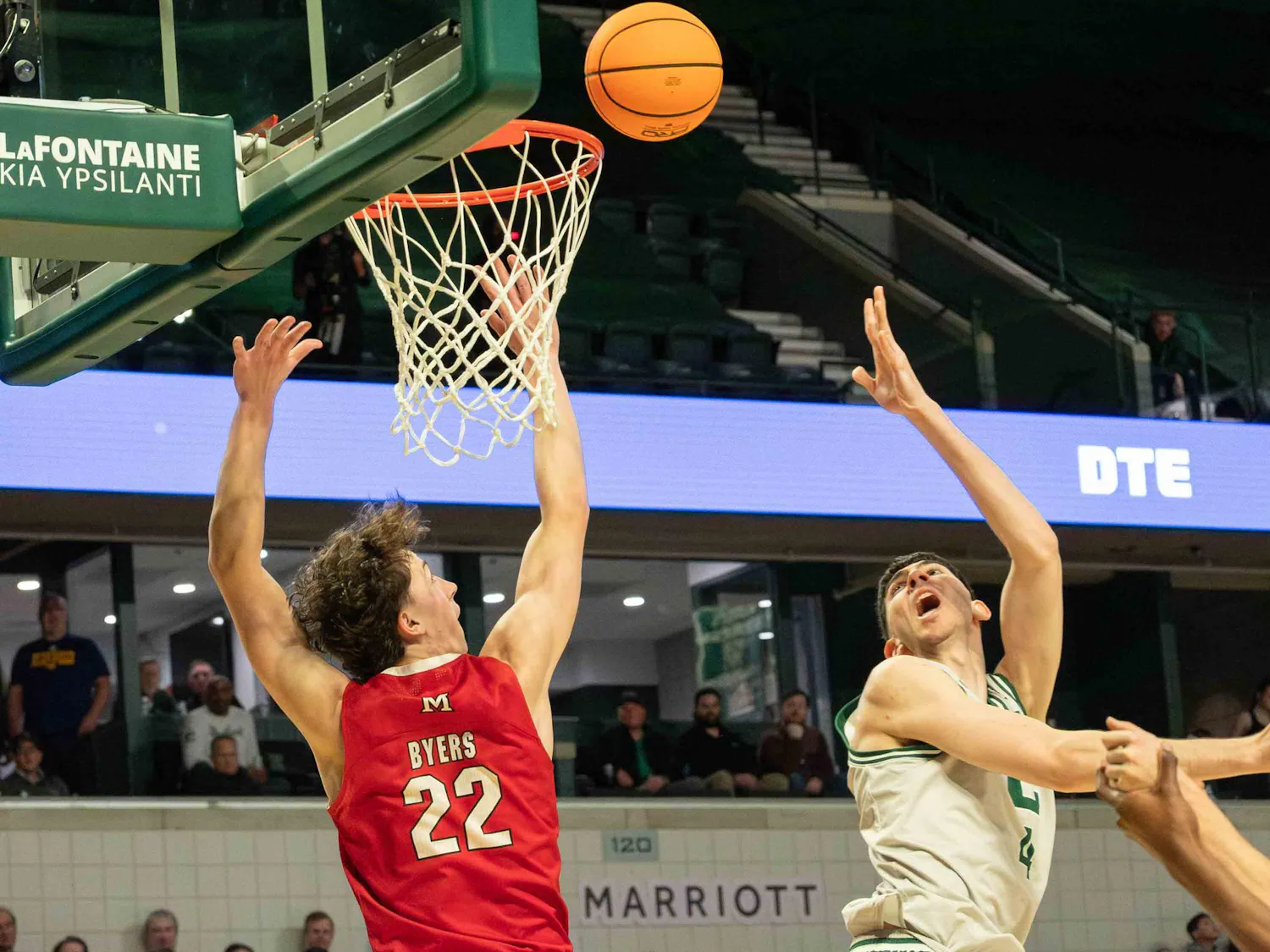An EMU basketball players throws the basketball behind him towards the net.