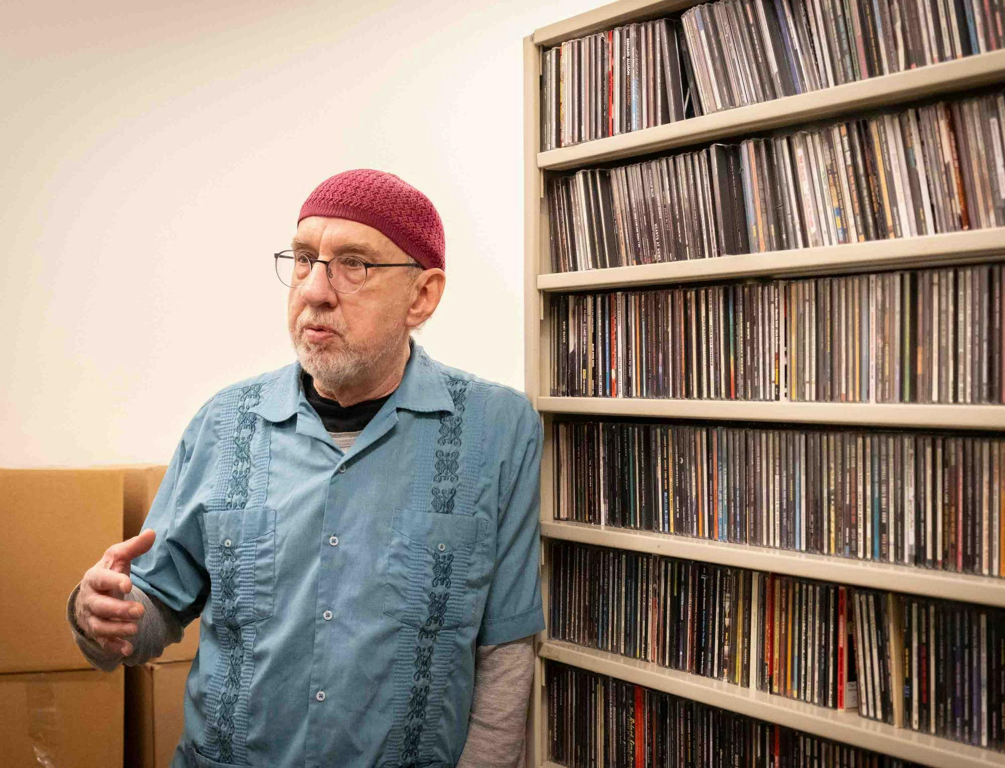 Marc Taras stands next to shelves filled with CDs.