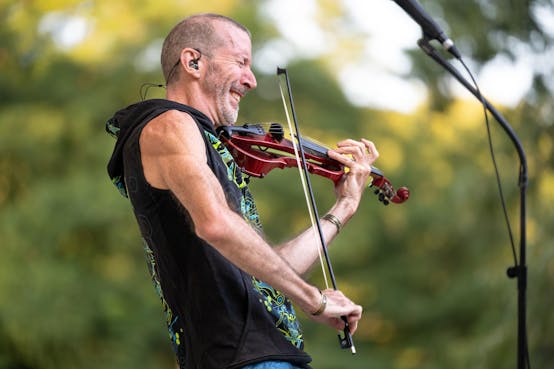 Musician Dixon Hammond, known as Dixon's Violin, smiles widely as he pulls his bow across his five-string electric violin.