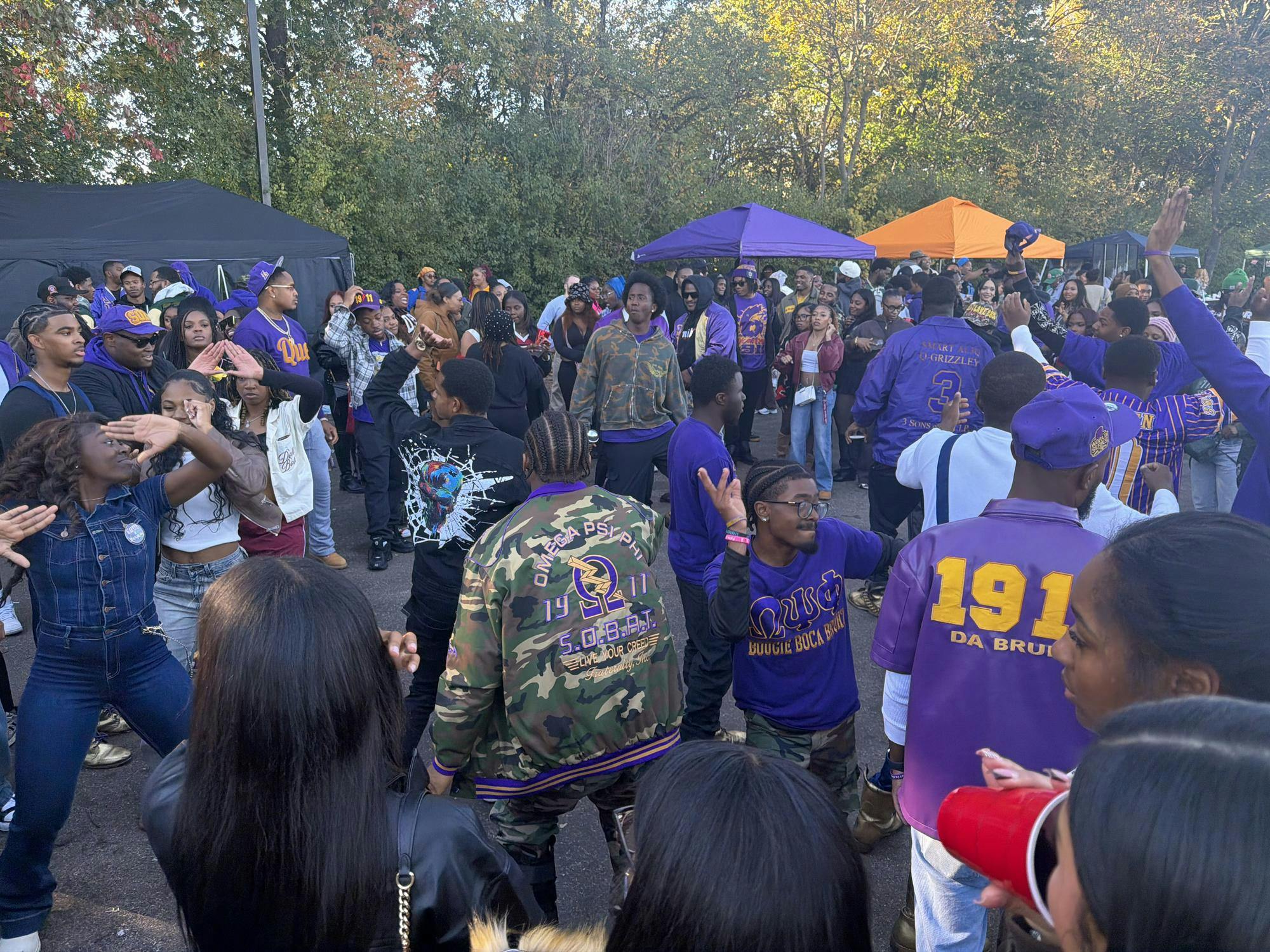 Fraternity and sorority members at EMU dancing together at EMUs Homecoming tailgate in the lot across from Rynearson Stadium.