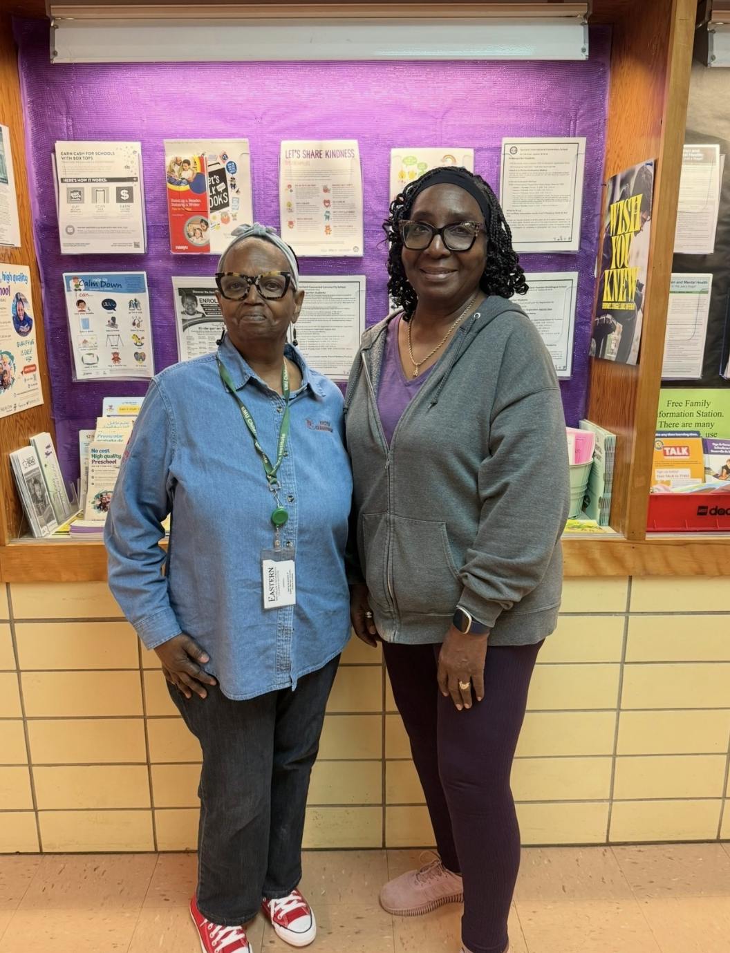 LaDonna Austin and Debra Williams-Smith stand together in front of a display full of posters and informative flyers.