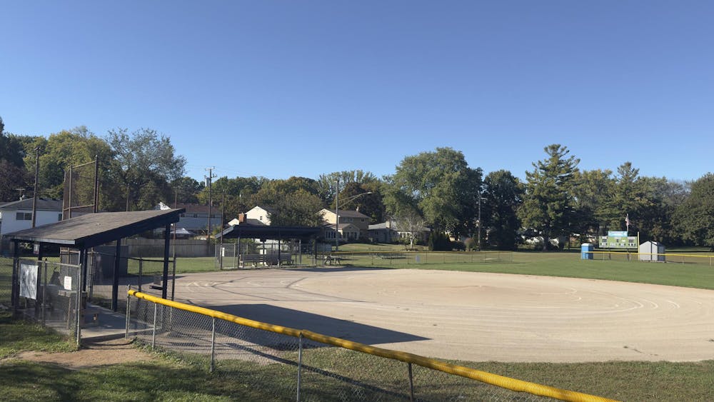 A baseball field surrounded by fencing, grass, and dugout areas for the team.