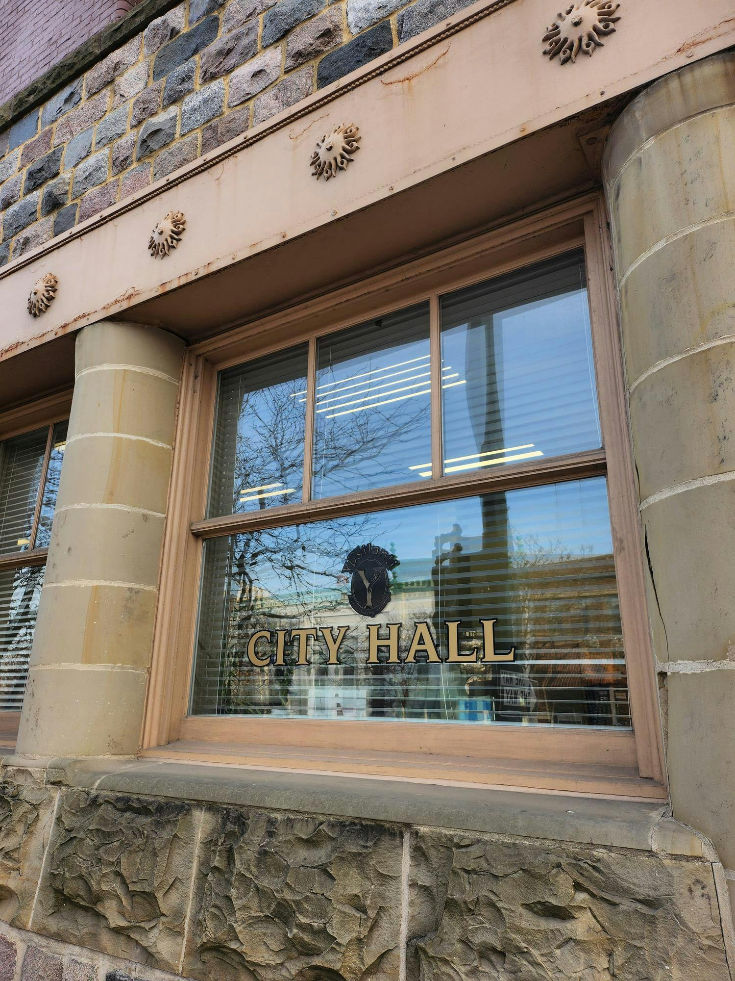 Image of a building with concrete columns and a window labeled "City Hall."