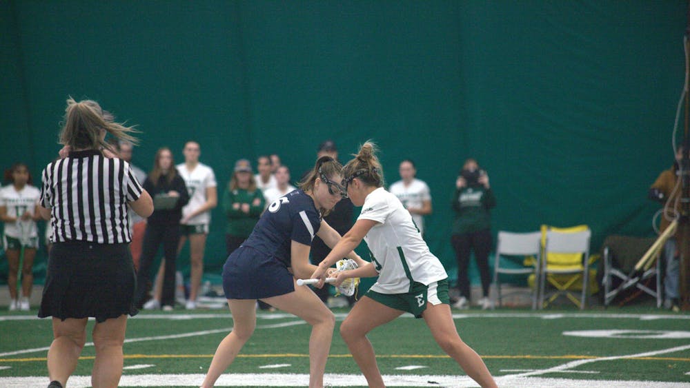 Women's lacrosse of opposing teams faceoff in the middle of the field before a play.