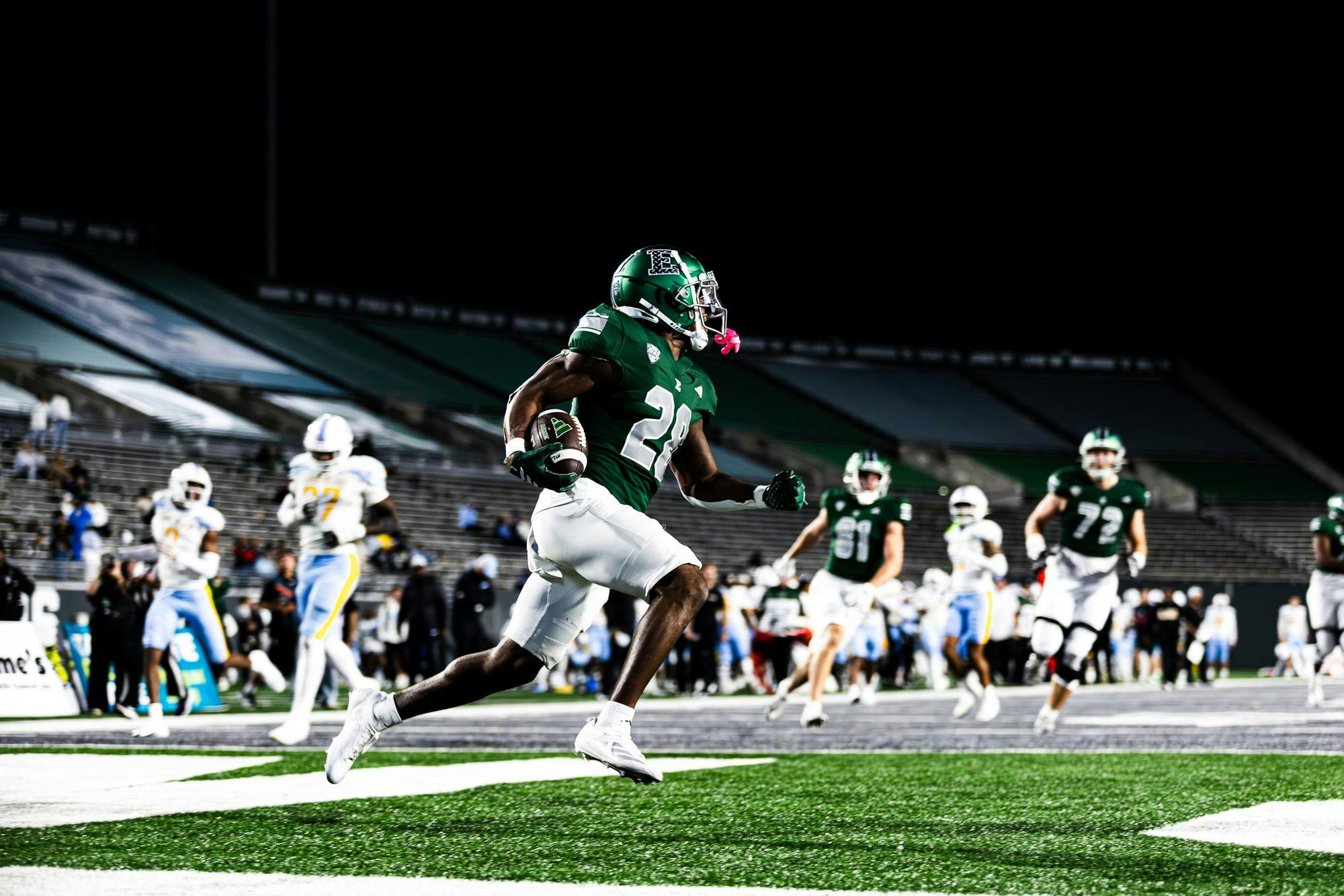 An Eastern Michigan running back galavants into the end zone with the football after scoring a touchdown. 