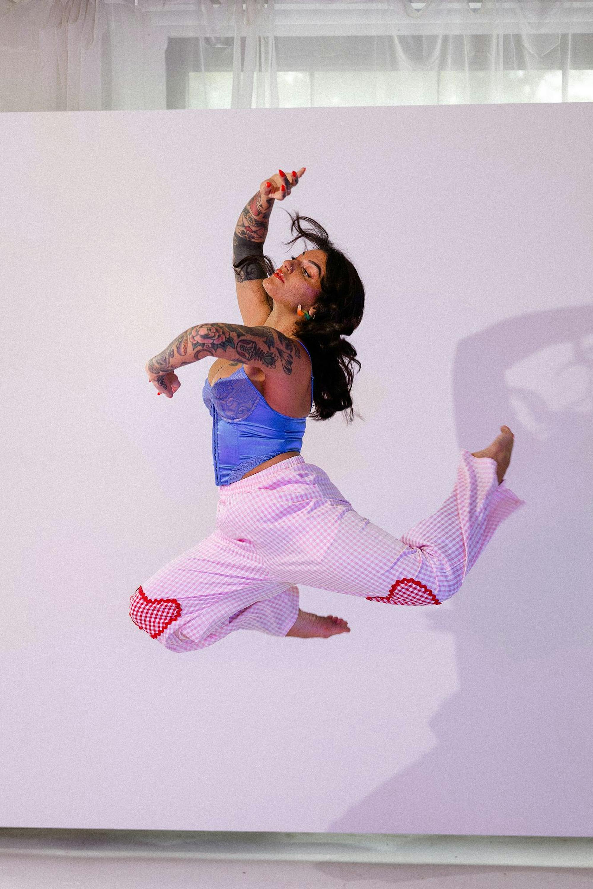 Chloe Gray leaps into the air with arms and legs bent backwards into a "C" shape.