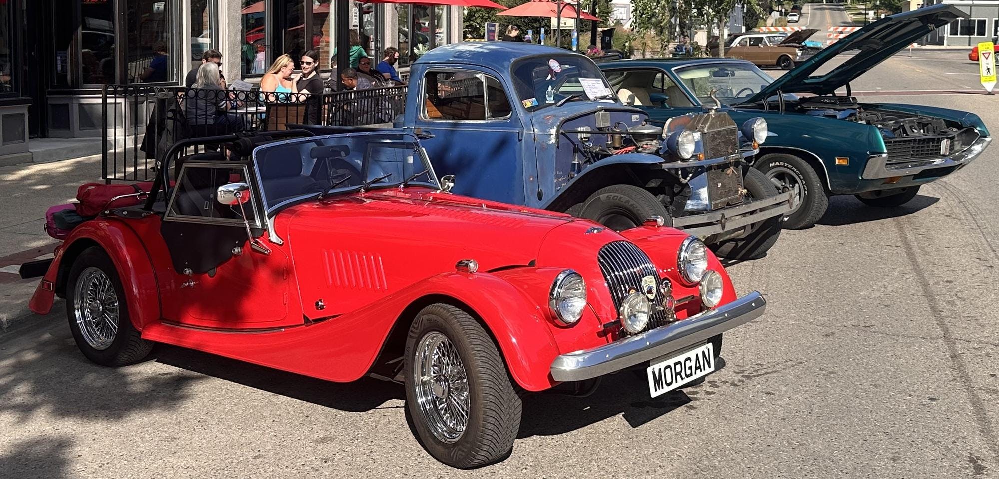 Three classic cars sit on display.