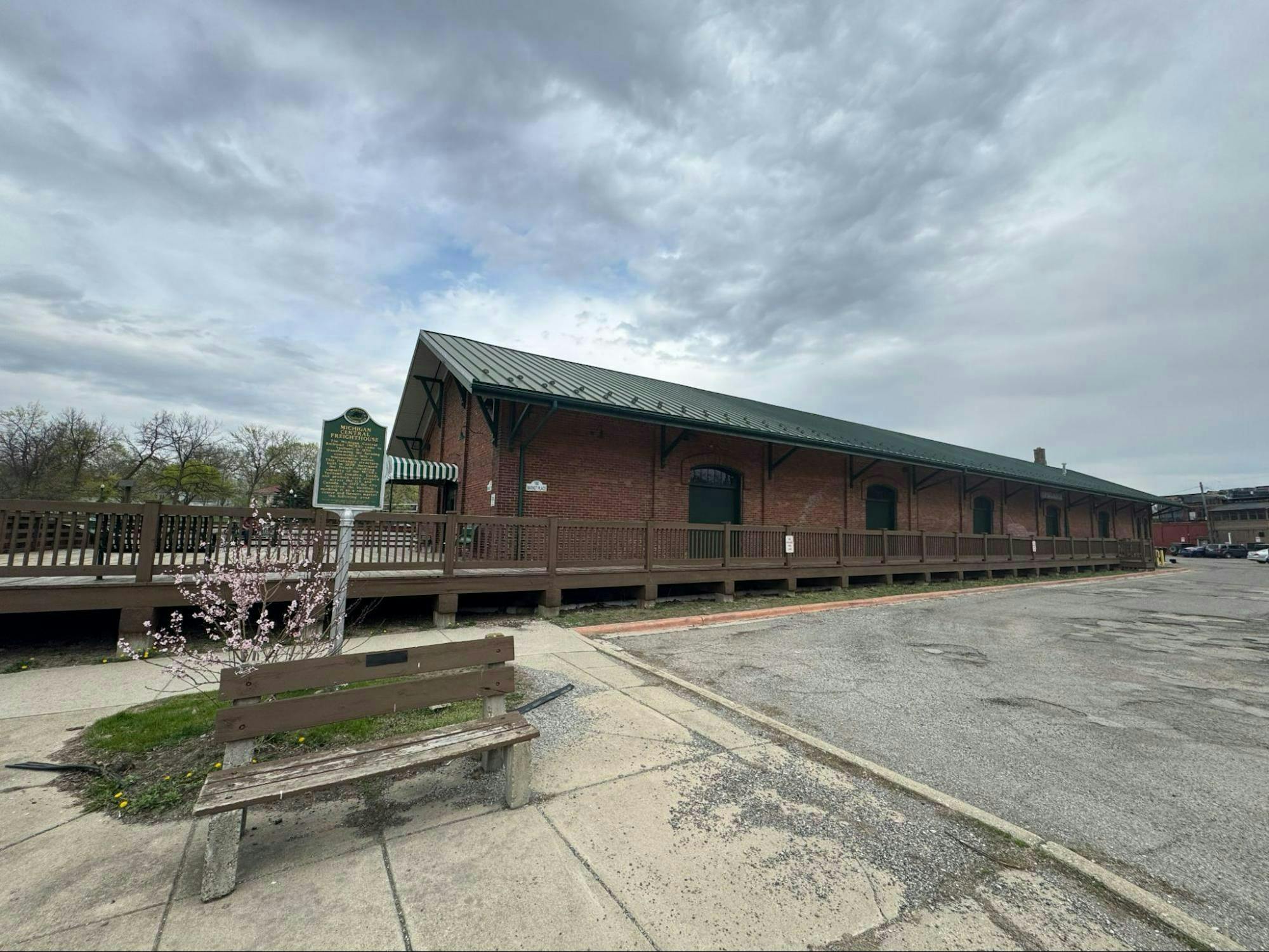 Long, single story, red brick building with a green roof. The building is a historical train depot.