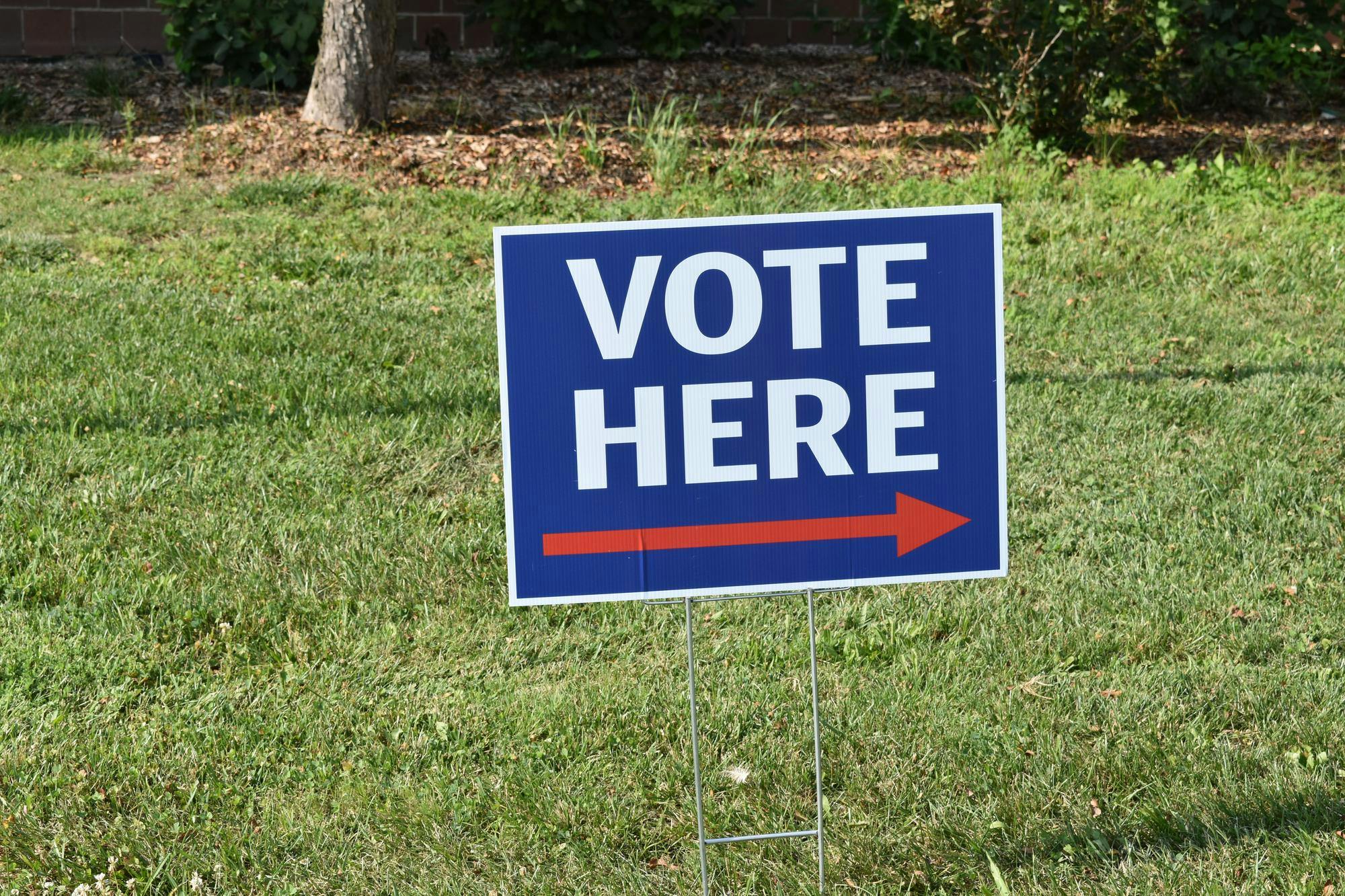 A red white and blue sign says "Vote Here" with a red arrow.