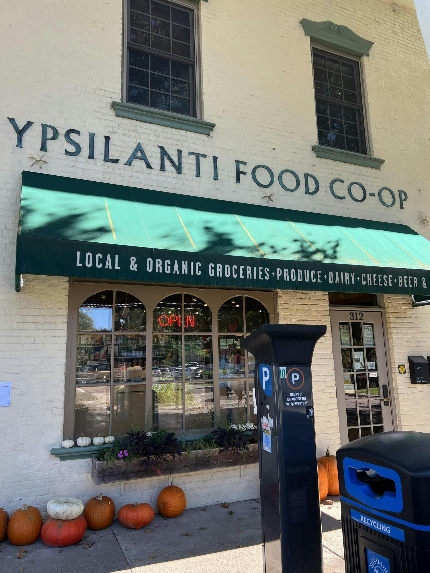 A sandy brick building with a bright green awning that houses Ypsilanti Food Co-op.