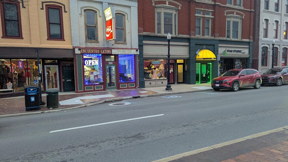 Downtown road with cars parked along sidewalks. Historic storefronts line the road.