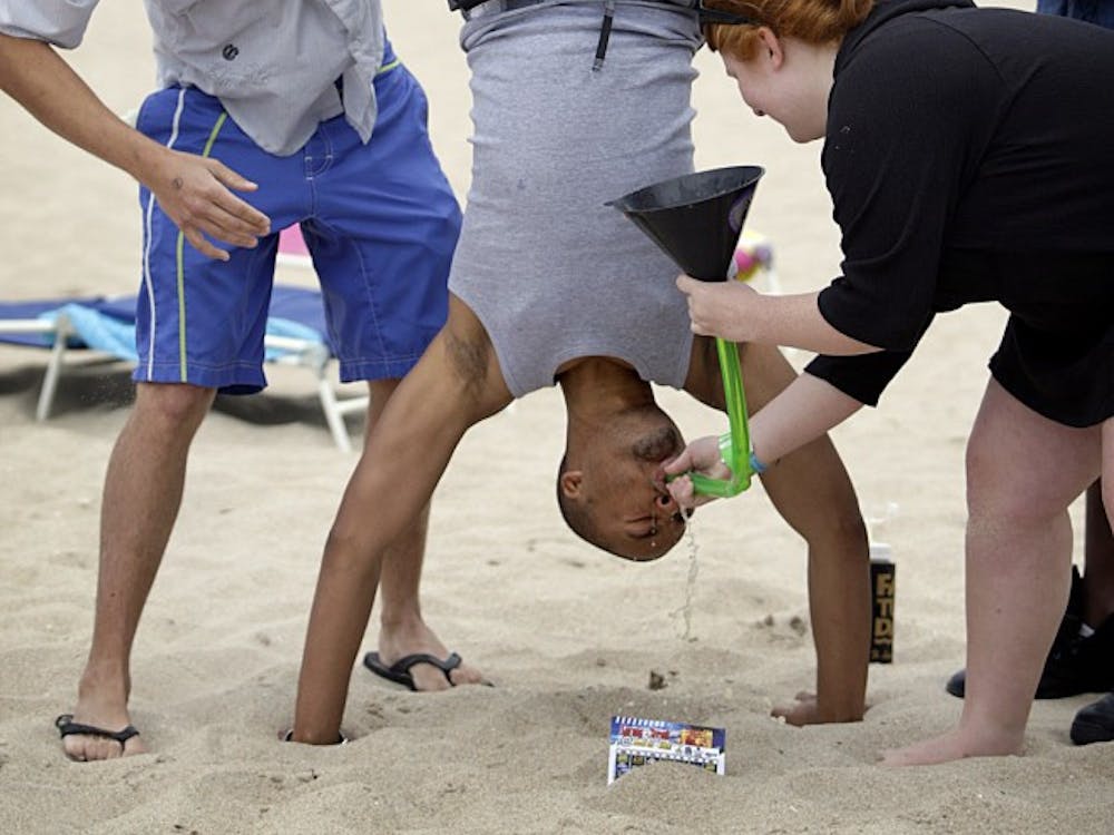 FAU student Schuyler Williams does a 'beer bong' with help from Indiana University student Megan Welihan, bottom right, as Ian Chance, left, helps support Williams in his gravity defying effort during spring break on Fort Lauderdale Beach, March 18, 2010, in Fort Lauderdale, Florida. (Patrick Farrell/Miami Herald/MCT)