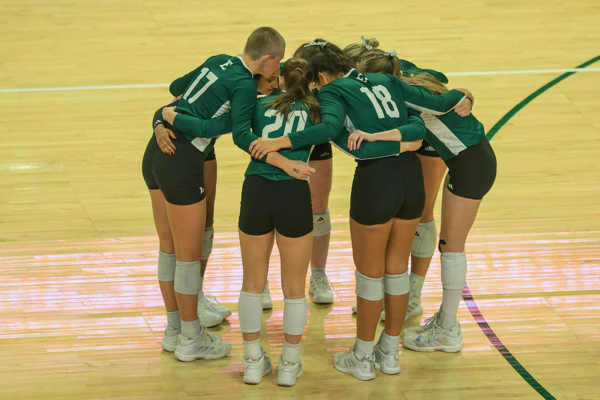 Eastern Michigan starting volleyball players huddle before their game