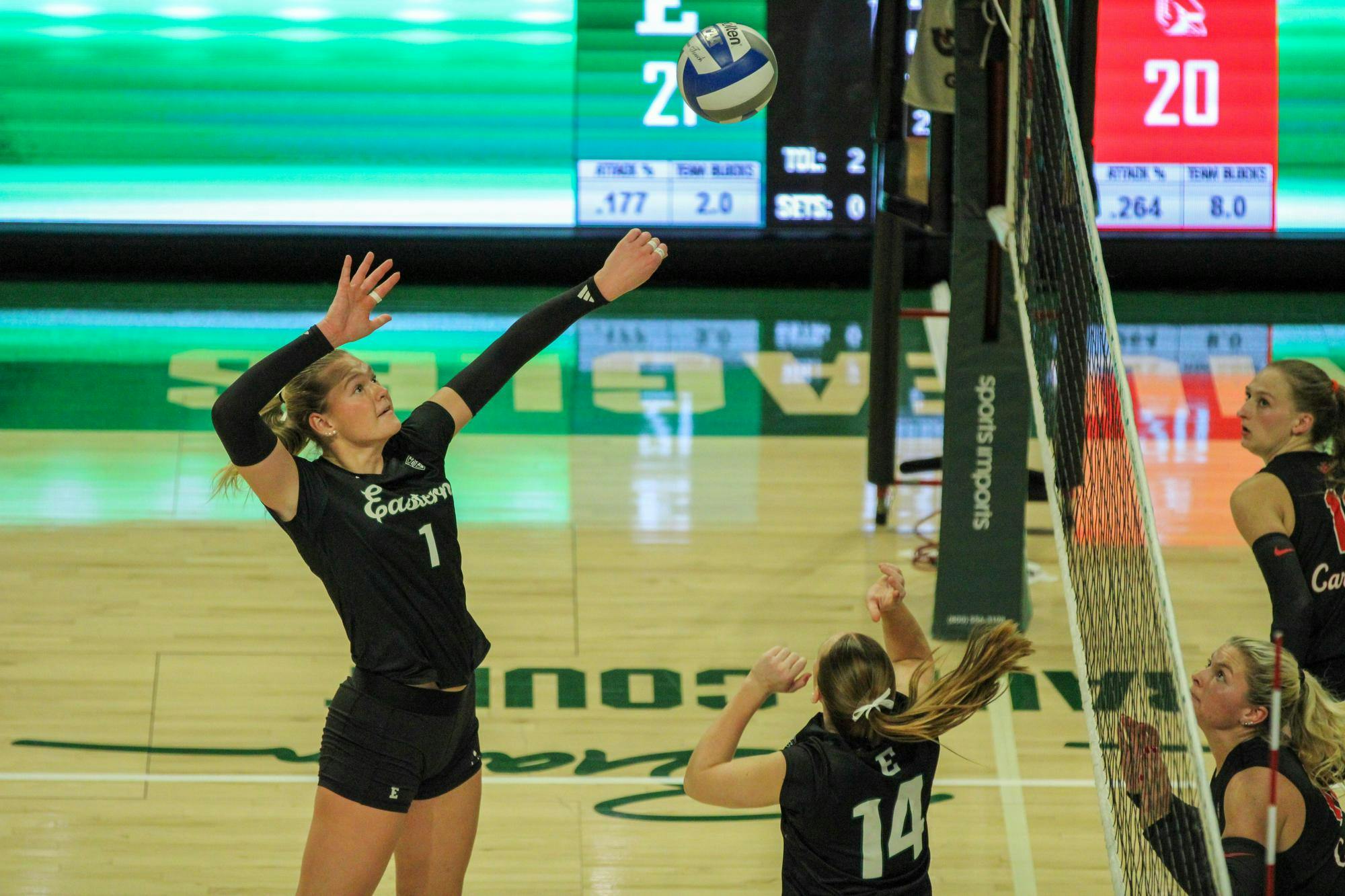 EMU player #1, in a black jersey, preparing to spike the volleyball.