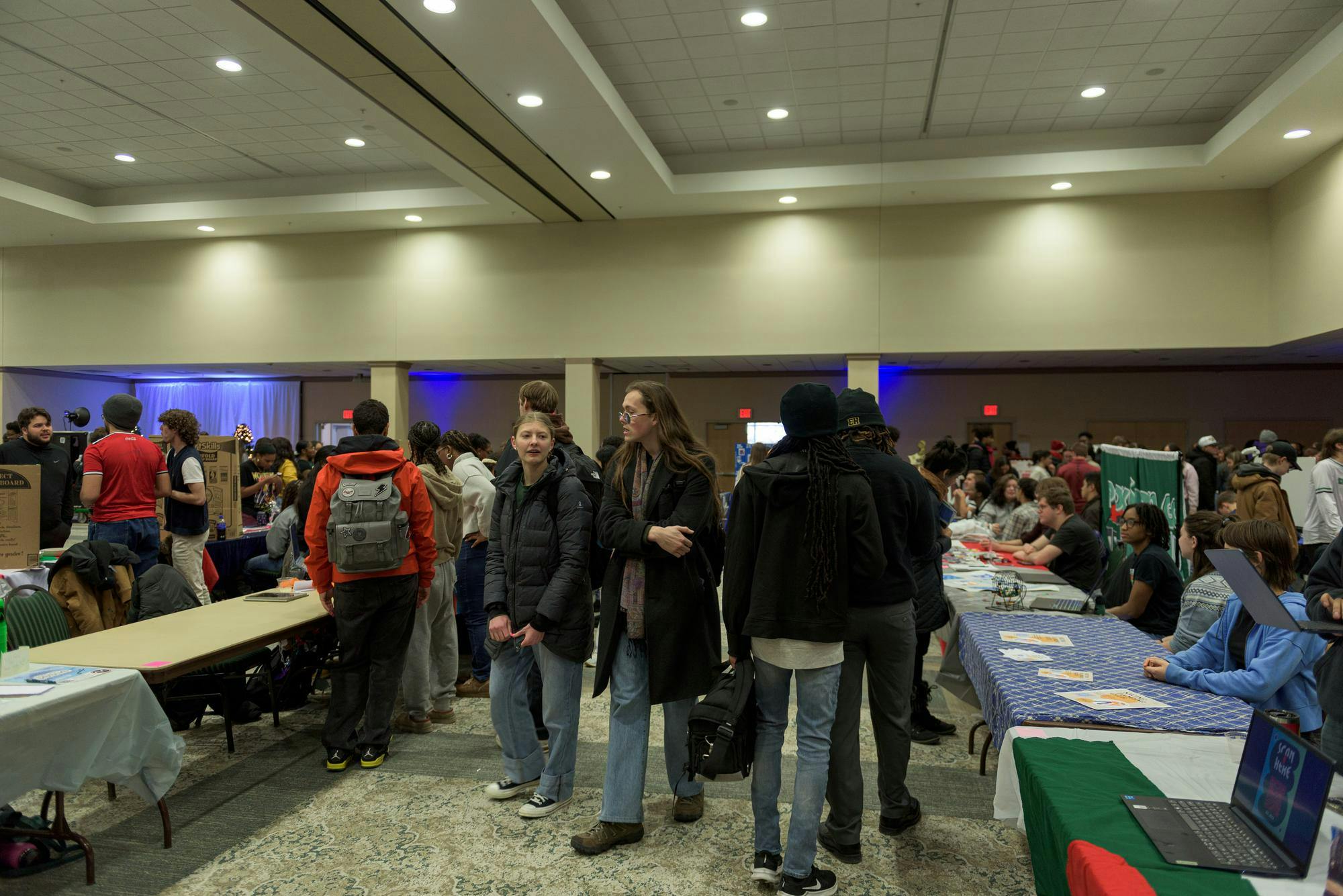 Students walk down a row with club and organization tables on either side of them.