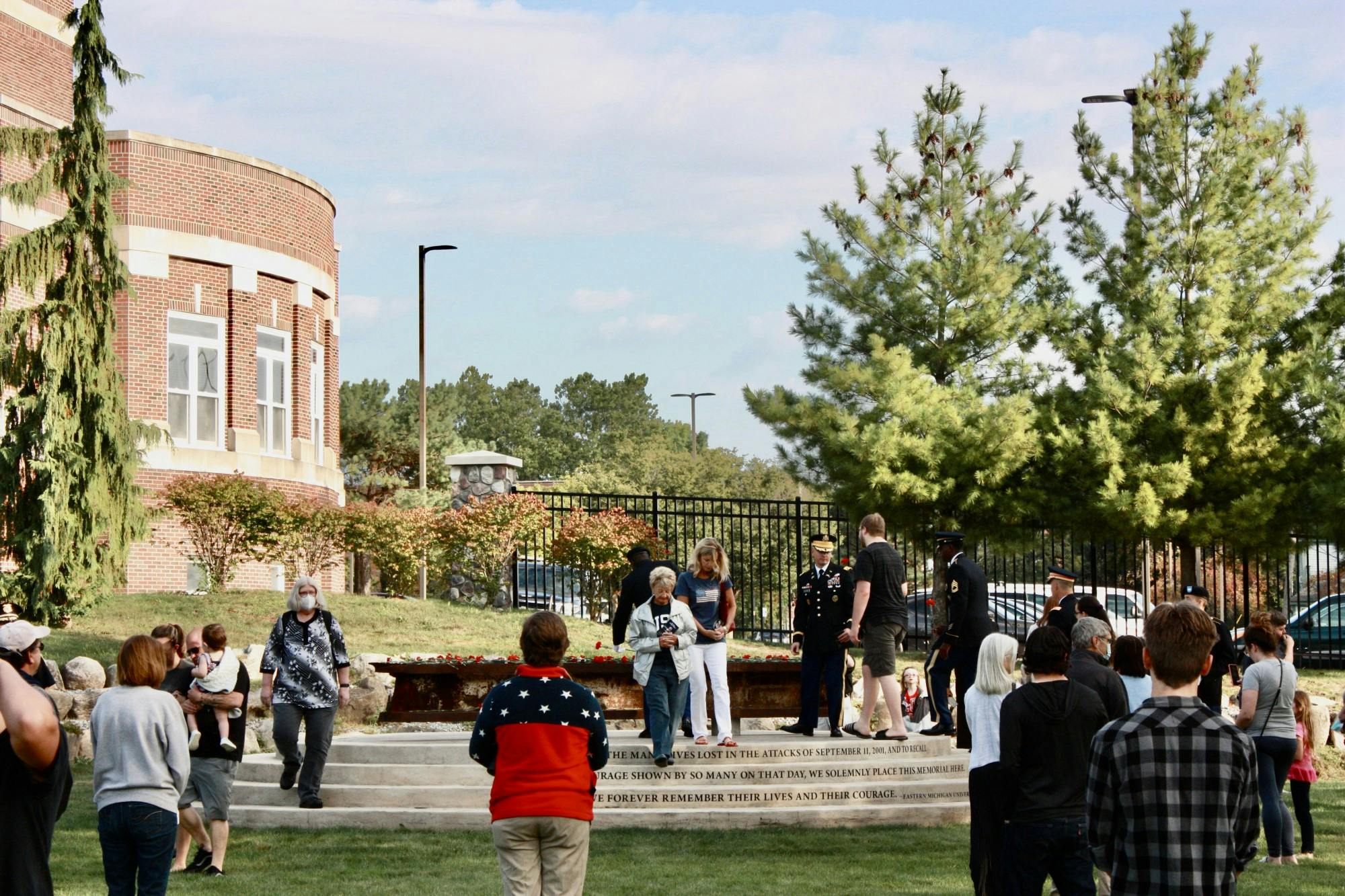 People gather around a memorial featuring a steel beam from the South Tower of the World Trade Center.