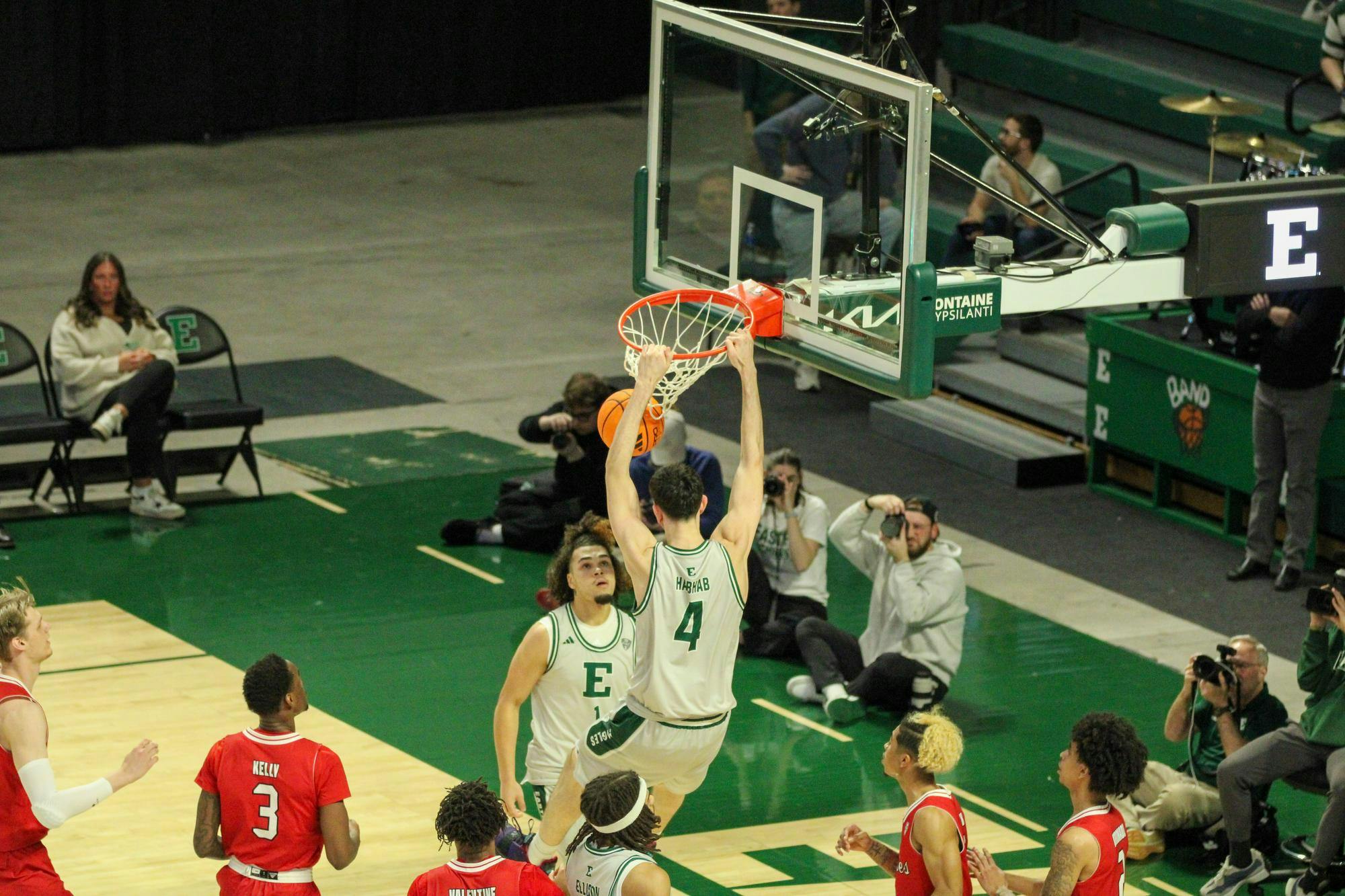 Eastern's player #4 is dunking the basketball and hanging on the basketball hoop.