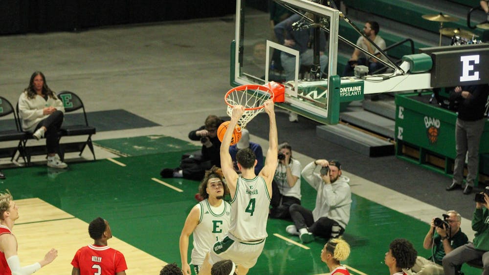 Eastern's player #4 is dunking the basketball and hanging on the basketball hoop.