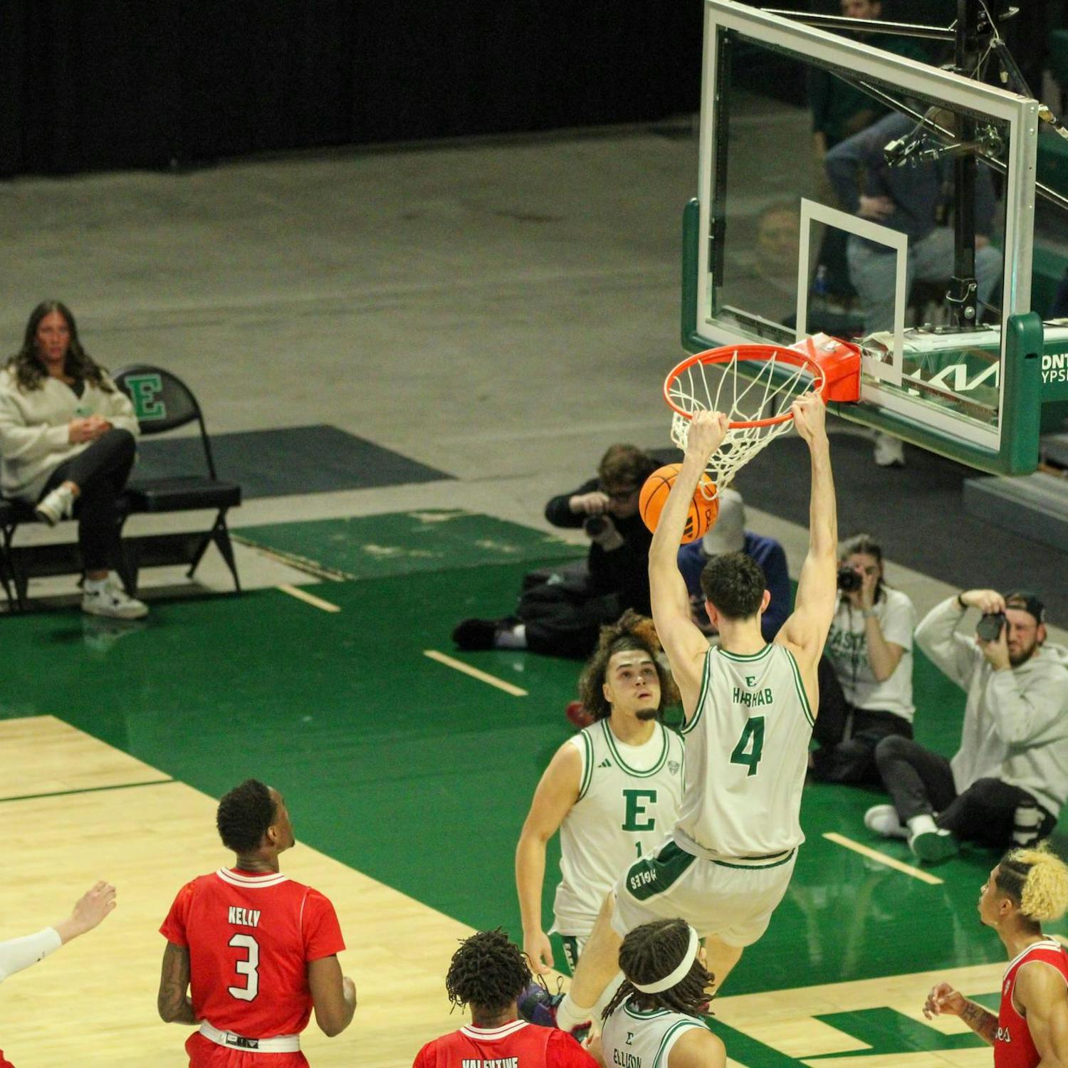 Eastern's player #4 is dunking the basketball and hanging on the basketball hoop.
