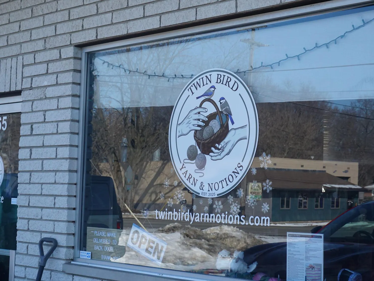 A view of the Twin Bird logo, which features two blue birds sitting on a basket of yarn with two hands reaching for the basket.