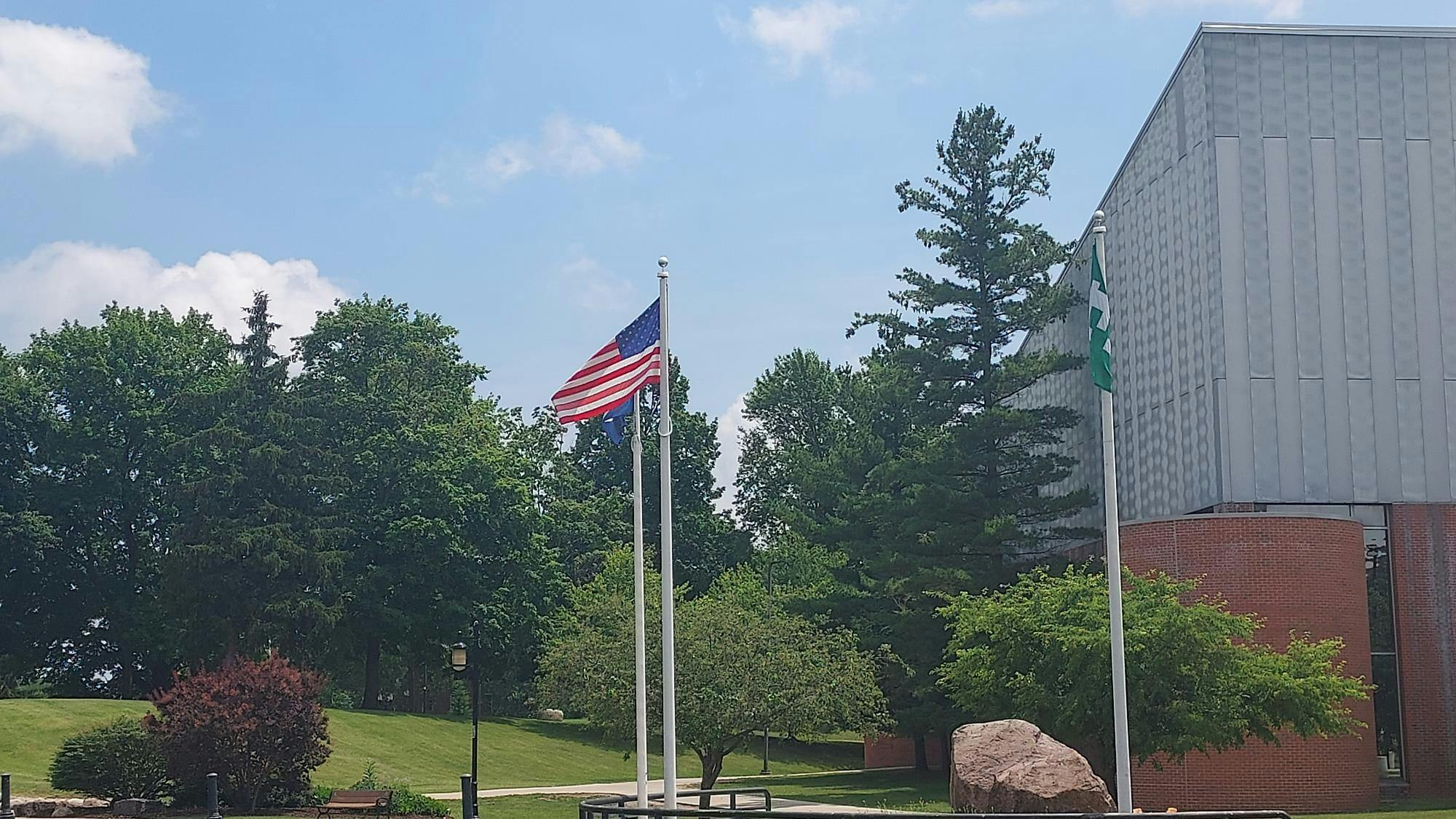 A United States flag blowing in the wind near the recreation area on Eastern Michigan University's campus. An EMU flag flies to its right. 