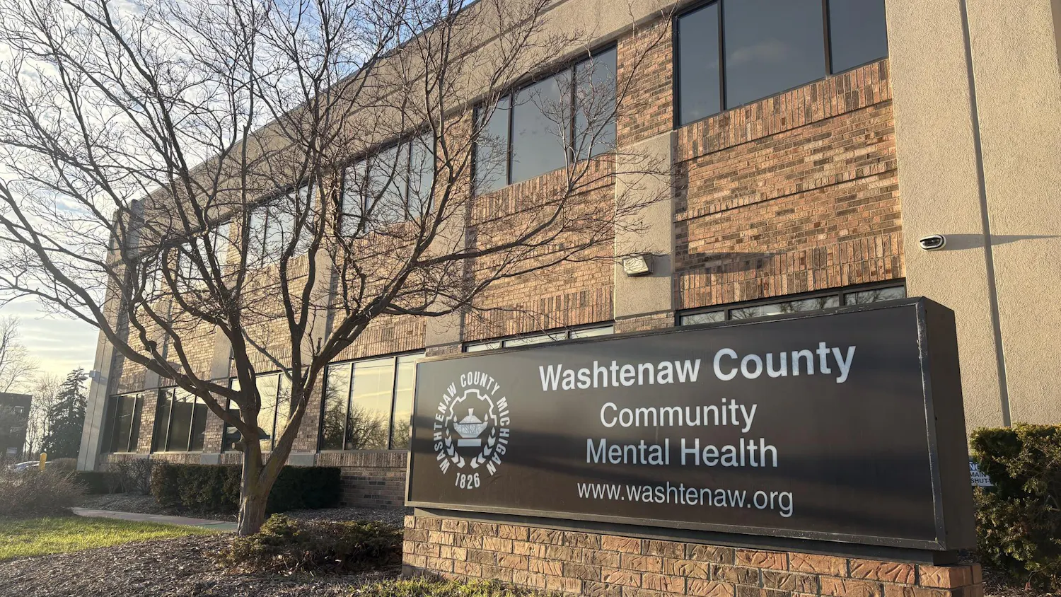 Brown and beige brick and concrete building. A sign in front reads, "Washtenaw County Community Mental Health, www.washtenaw.org."