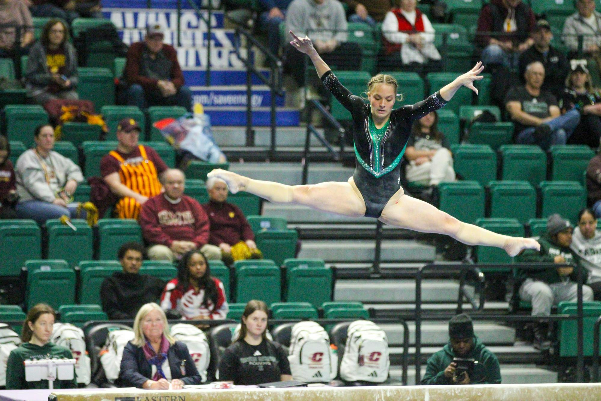 EMU gymnast, Macy Nihart, doing the splits in the air during her beam routine. 
