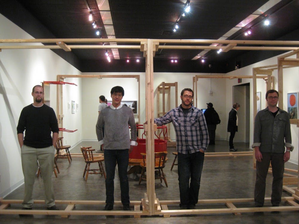 From left, Jason Ferguson, Gregory Tom, Jason DeMarte and Brian Spolans stand inside the piece “Showtime,” which Tom created out of two-by-fours. Tom wanted the piece to challenge those entering the New Faculty Exhibition in the Ford gallery.