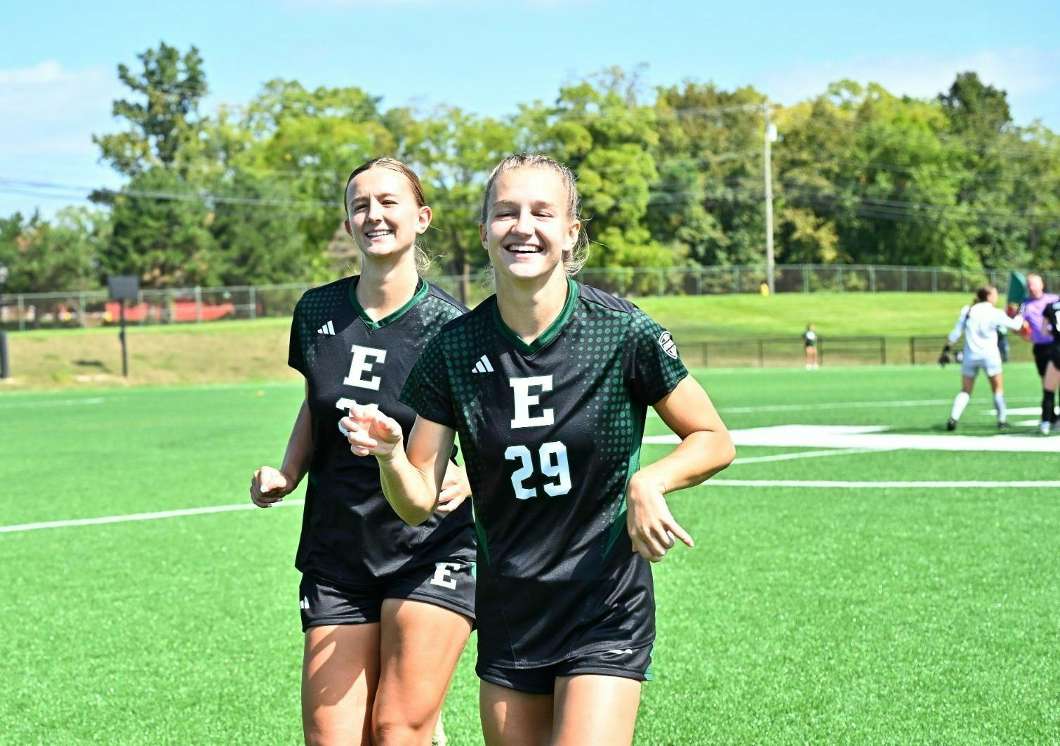 Kate Robinson runs across the soccer field with another teammate on a sunny day.