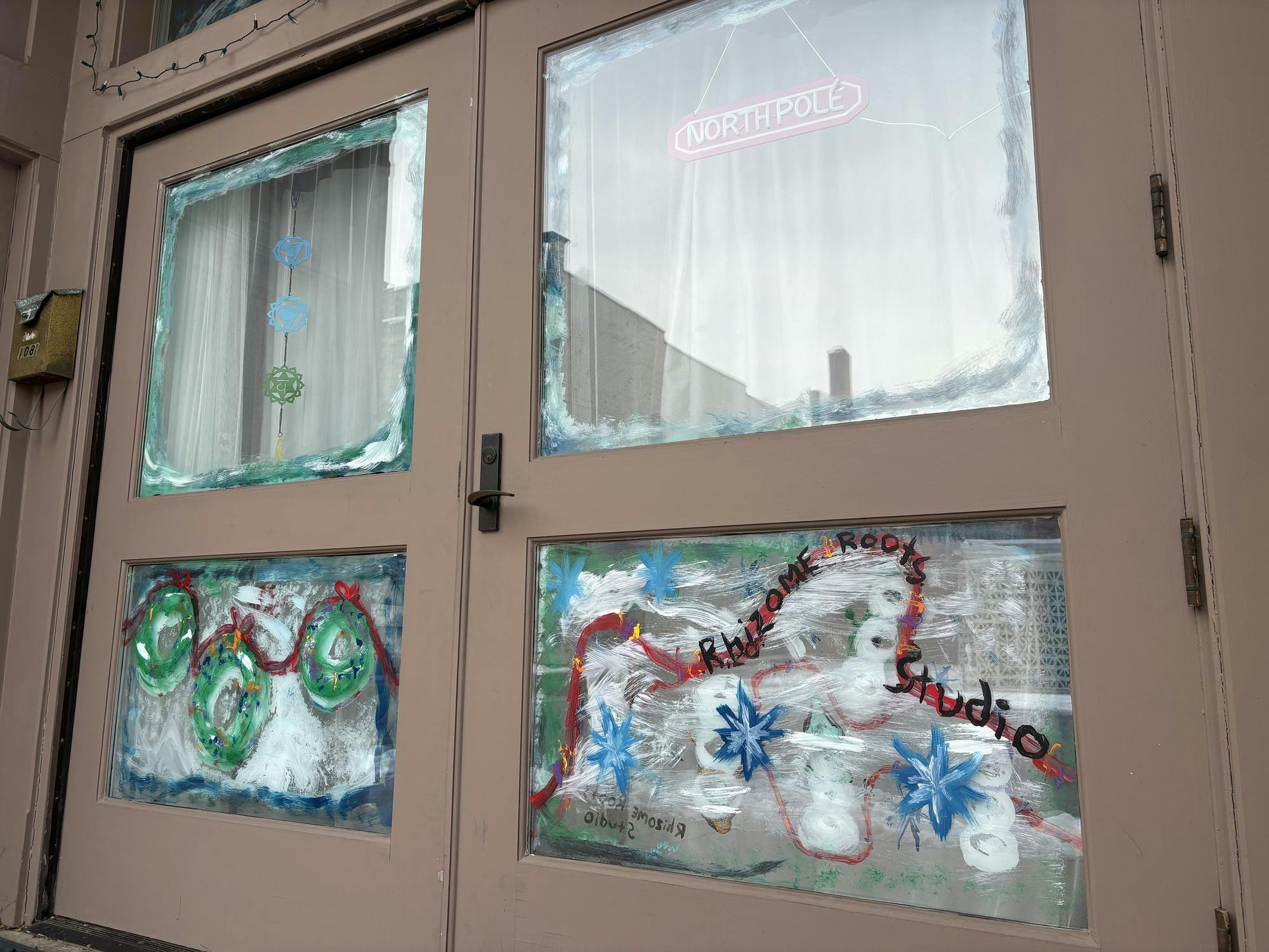 Image of two glass doors with brown framing. The glass doors are decorated with drawn on holiday and winter scenes. 