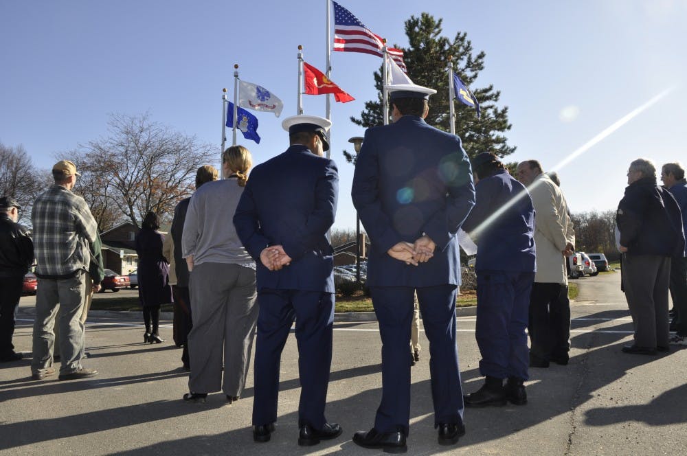 Two veterans of the U.S. Coast Guard stand in front of a new set of flags near Westview Apartments, which was the site of a ceremony Wednesday that saluted veterans. Every branch of the military is recognized by its own flag. 