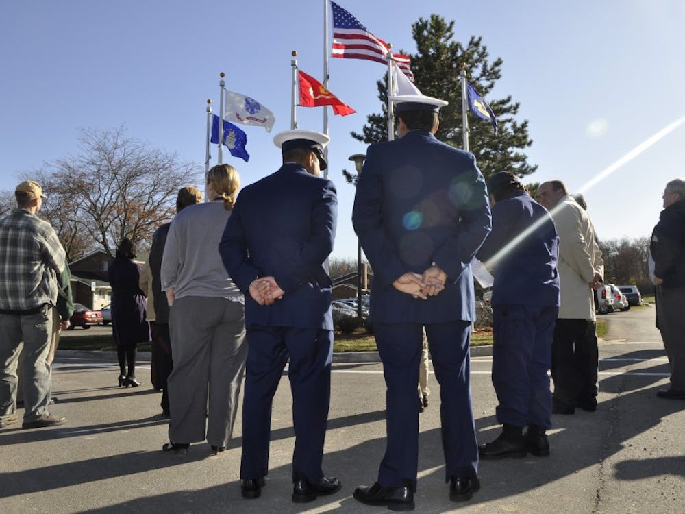 Two veterans of the U.S. Coast Guard stand in front of a new set of flags near Westview Apartments, which was the site of a ceremony Wednesday that saluted veterans. Every branch of the military is recognized by its own flag. 
