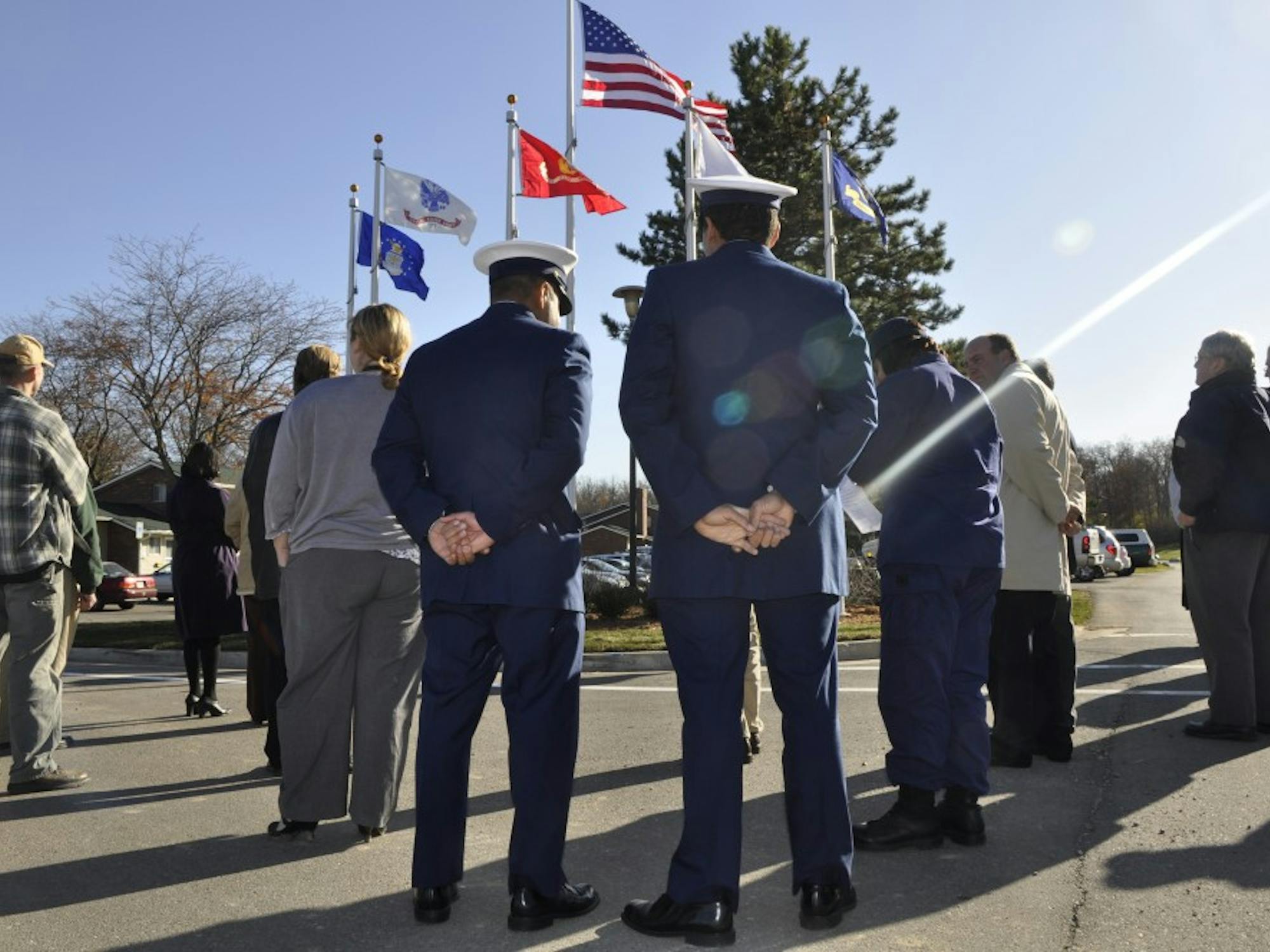 Two veterans of the U.S. Coast Guard stand in front of a new set of flags near Westview Apartments, which was the site of a ceremony Wednesday that saluted veterans. Every branch of the military is recognized by its own flag. 