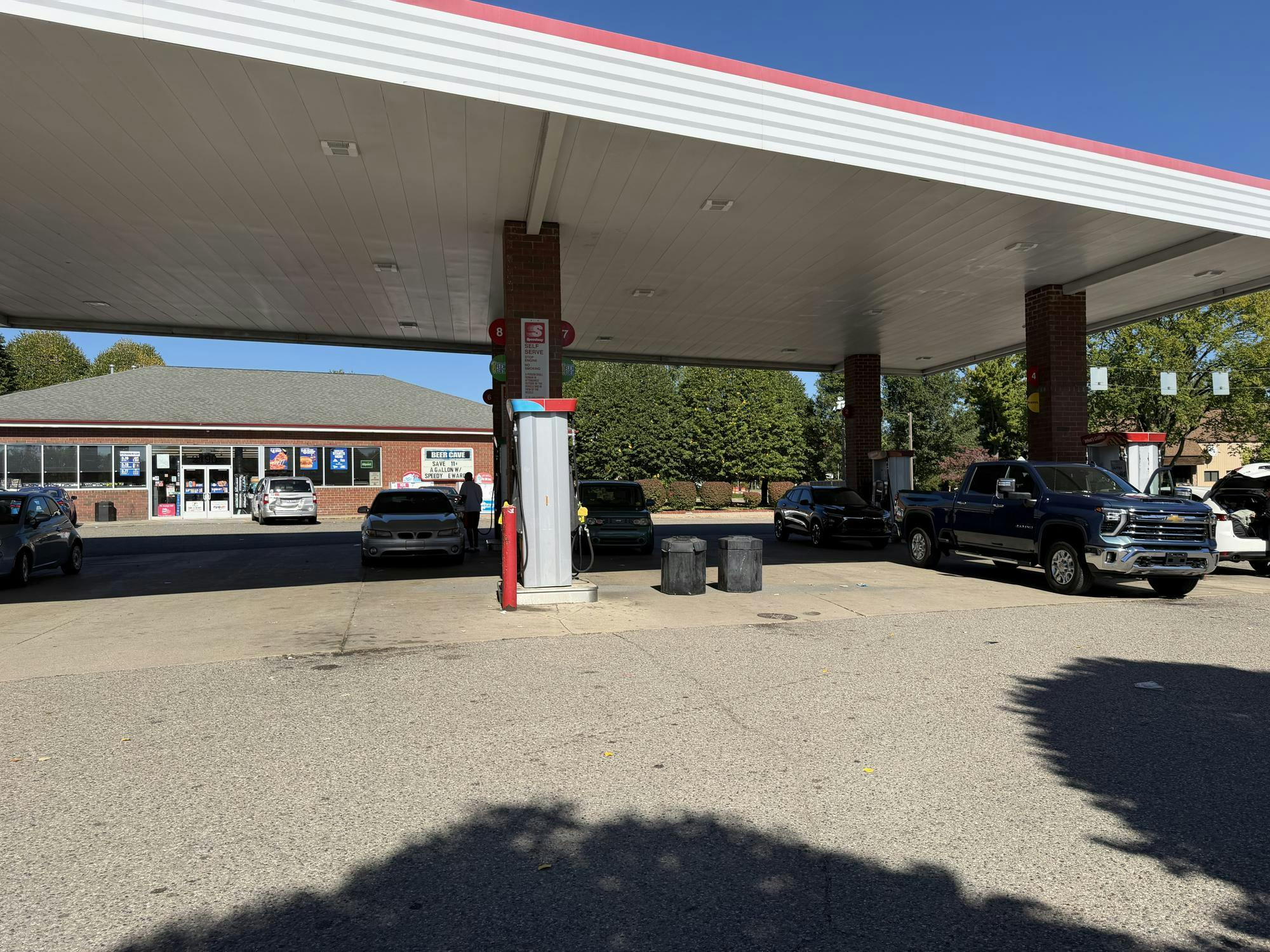 Vehicles park at a gas station in front of a building.