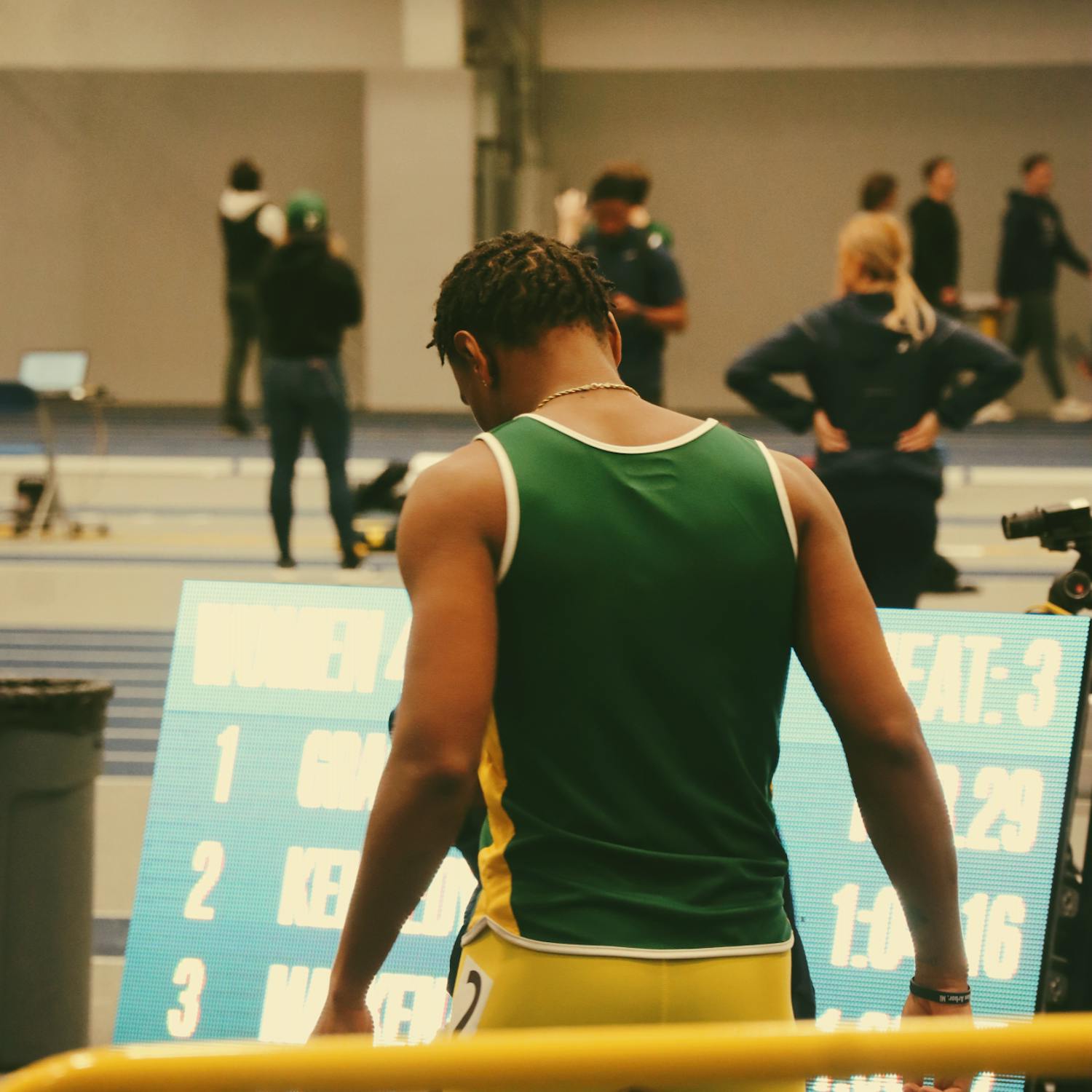 Image shows a student athlete with their back to the camera, wearing a green jersey.