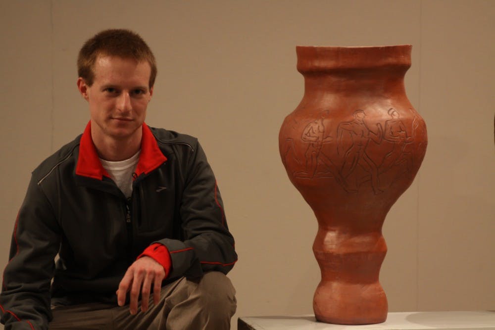 	Eastern senior Ben Thompson poses next to his terracotta pot. His pot, along with his classmates’, were a part of the Big Pots Show at Ford on Tuesday.