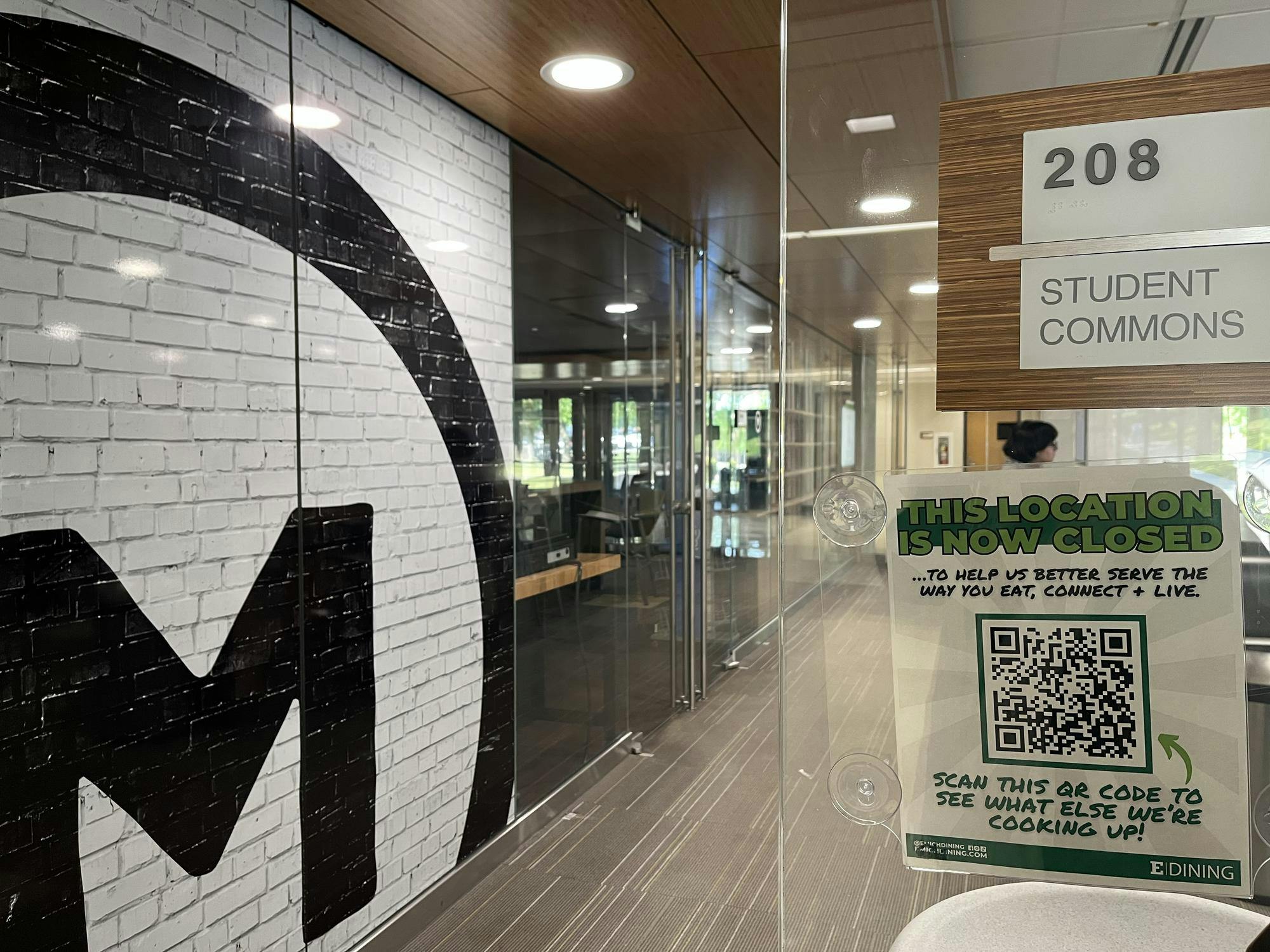 Closed market is shown through the doorway of a transparent glass wall. Sign outside the doorway reads, "This location is now closed."