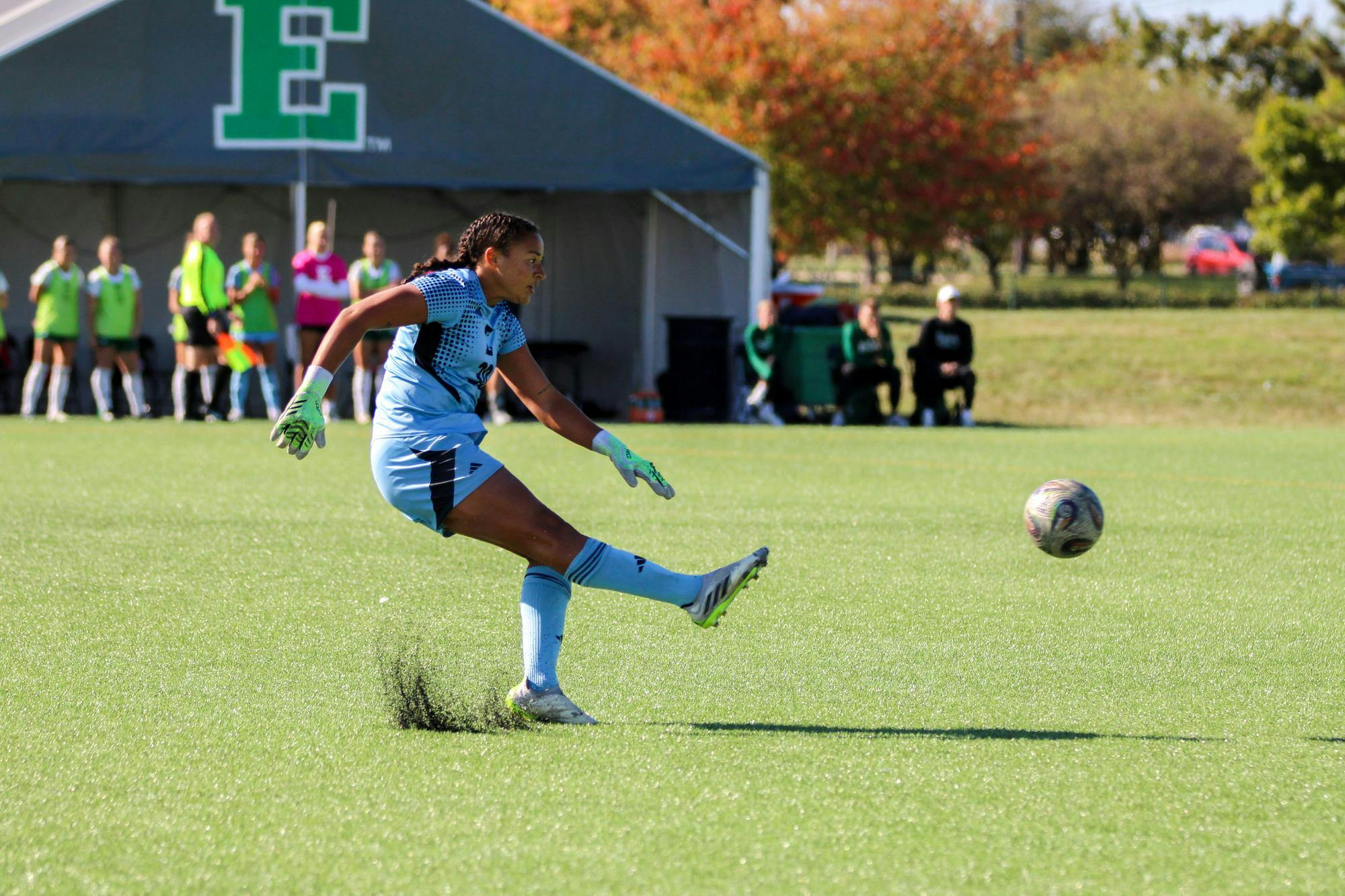 EMU player, in the white jersey, kicking the soccer ball