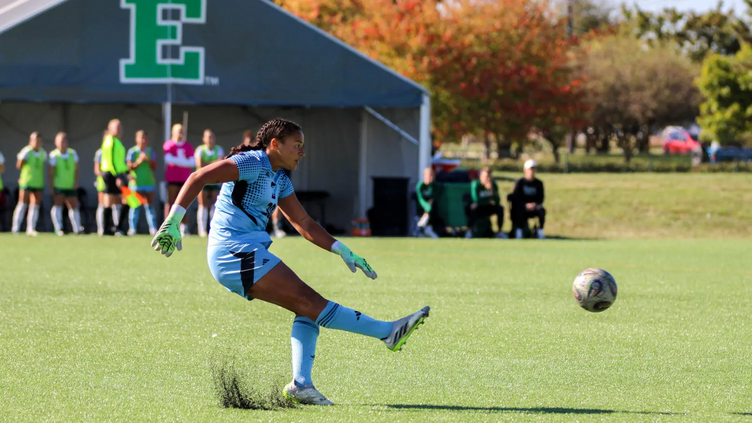 EMU player, in the white jersey, kicking the soccer ball