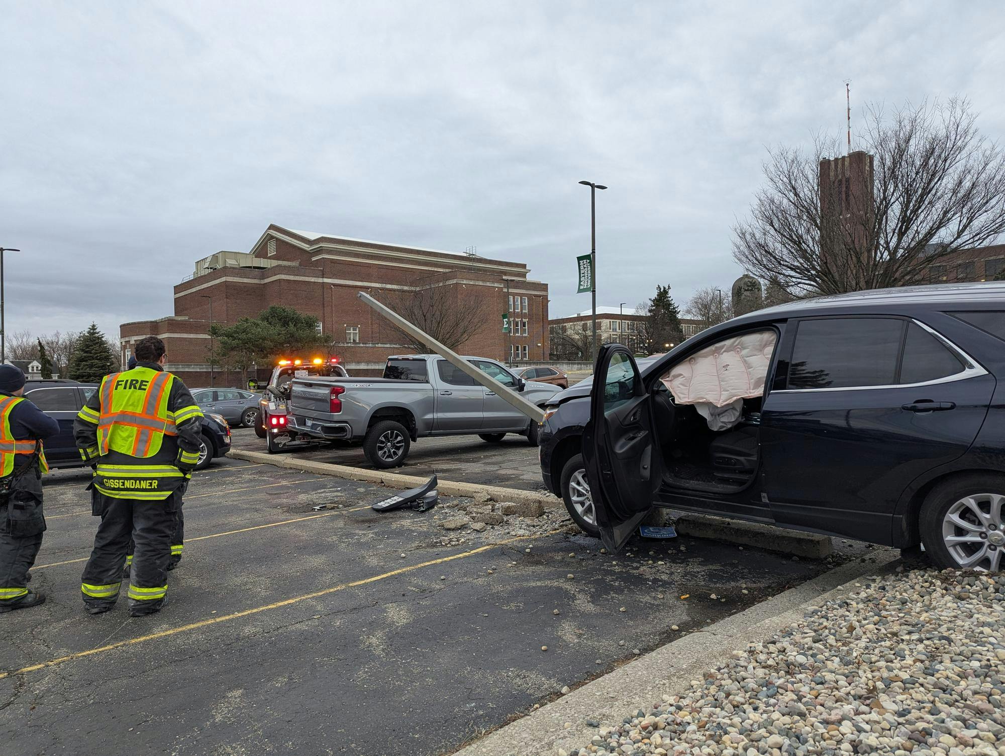 Firefighters stand and watch a tow truck at the scene of a car accident.
