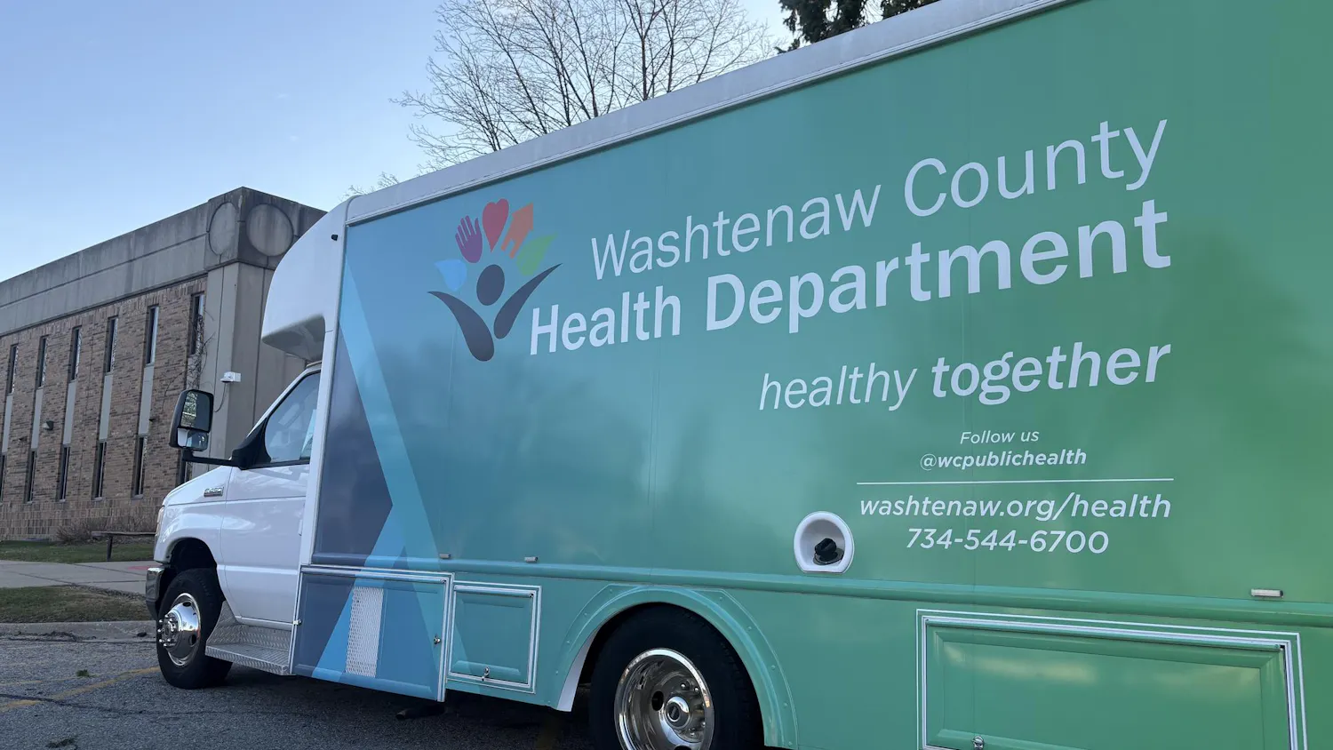Large commercial van parked along sidewalk. Graphics on the van read "Washtenaw County Health Department, healthy together."