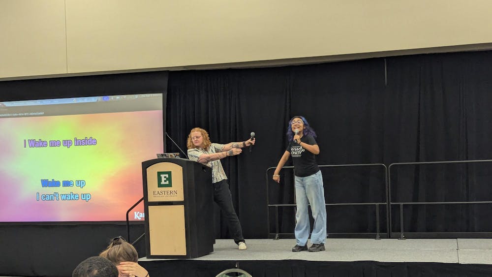 Two individuals holding microphones sing karaoke.