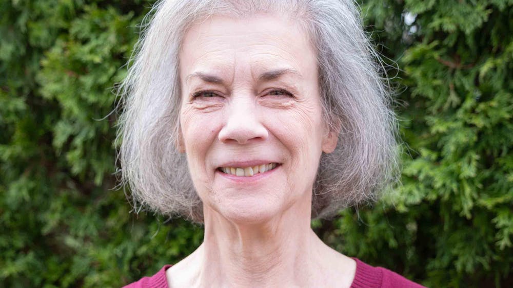 Sally Wright Day smiles outdoors in front of green foliage.