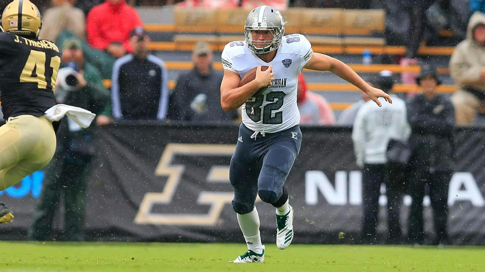 Gunnar Oakes runs with the football in the rain during pre-game warmups while playing for Eastern Michigan University.