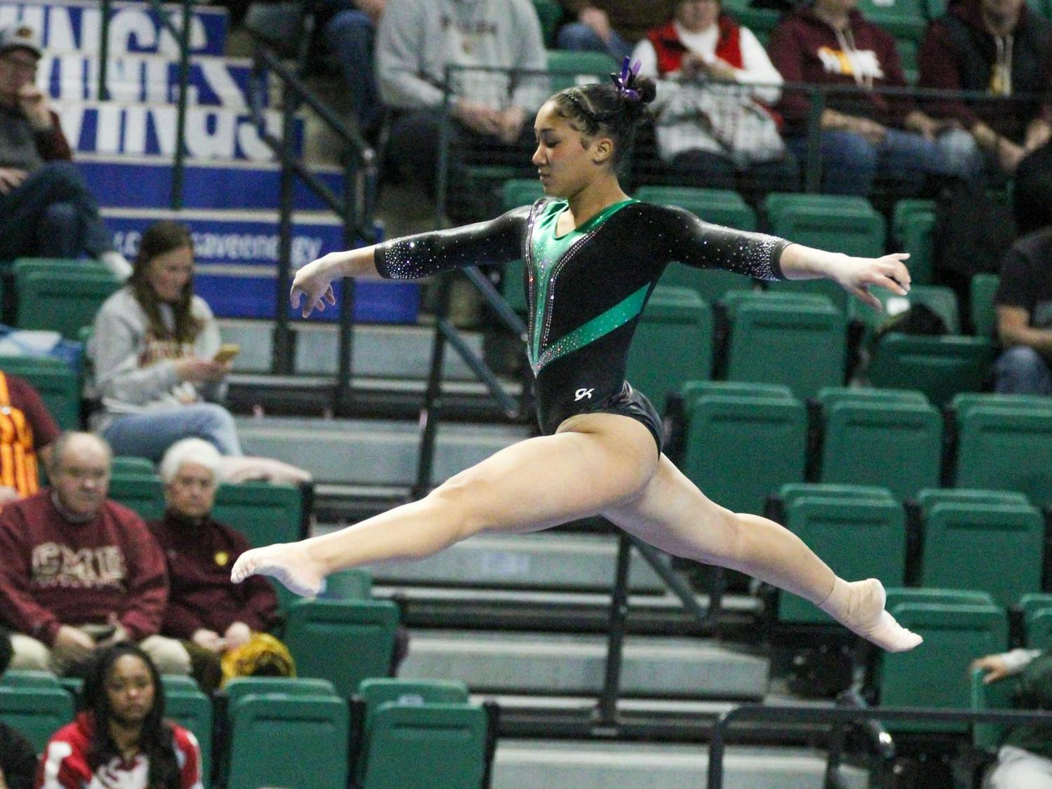 EMU gymnast, Kendall Landry, doing a front split in the air during her beam routine.