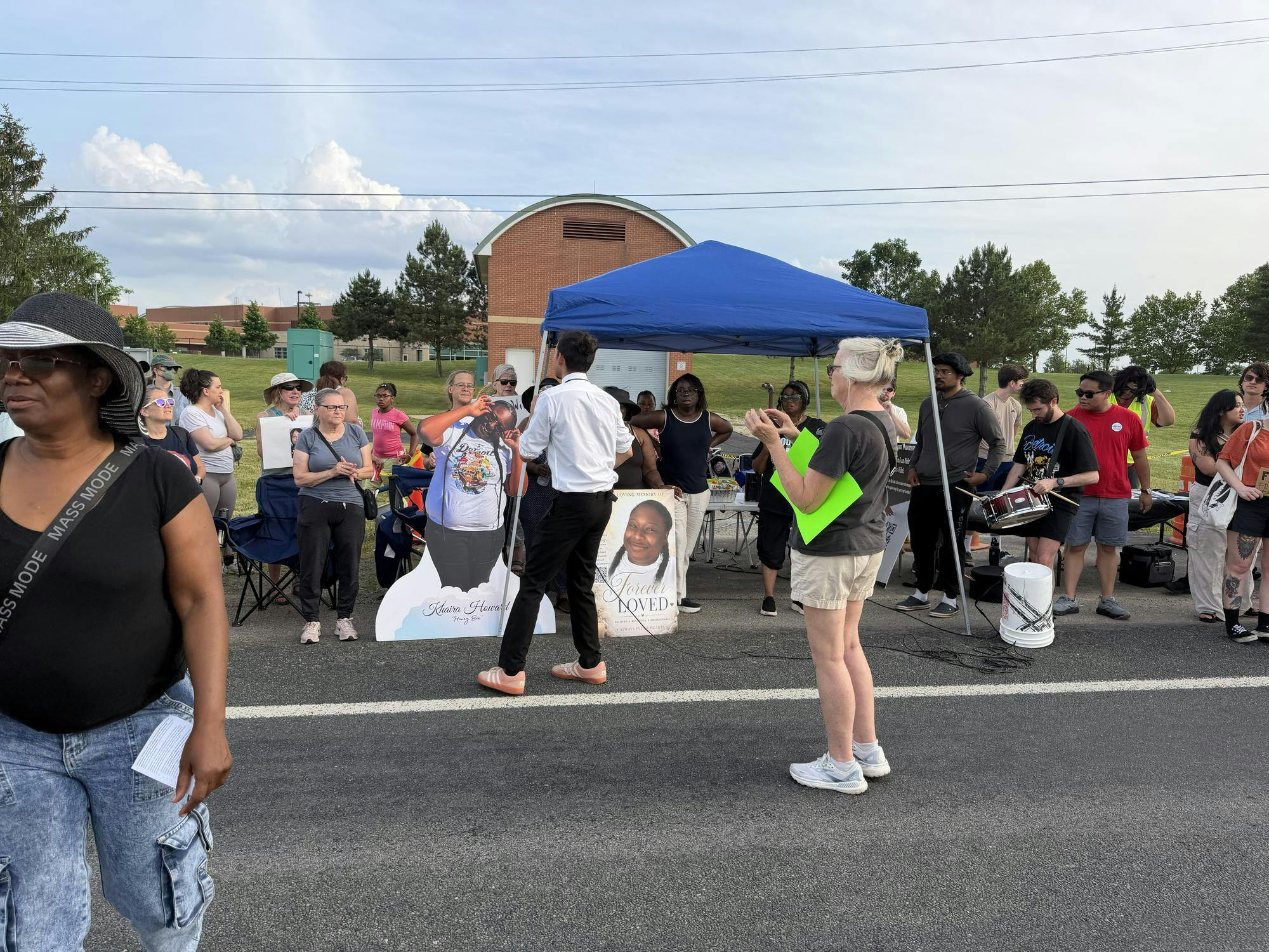 Protestors on the side of the road have signs with pictures of Khaira Howard that say "forever loved."