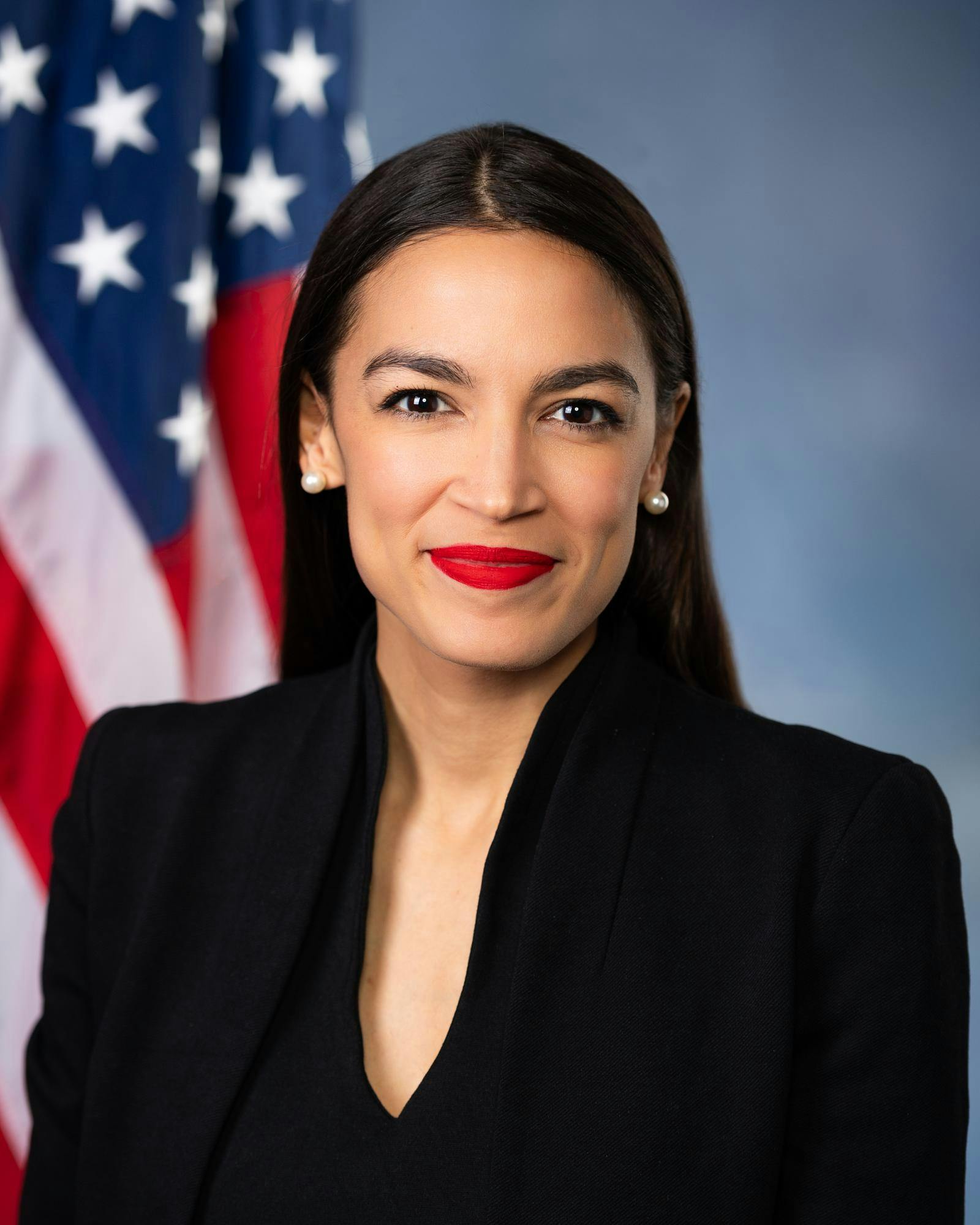 Headshot of Alexandria Ocasio-Cortez with an American flag in the background.