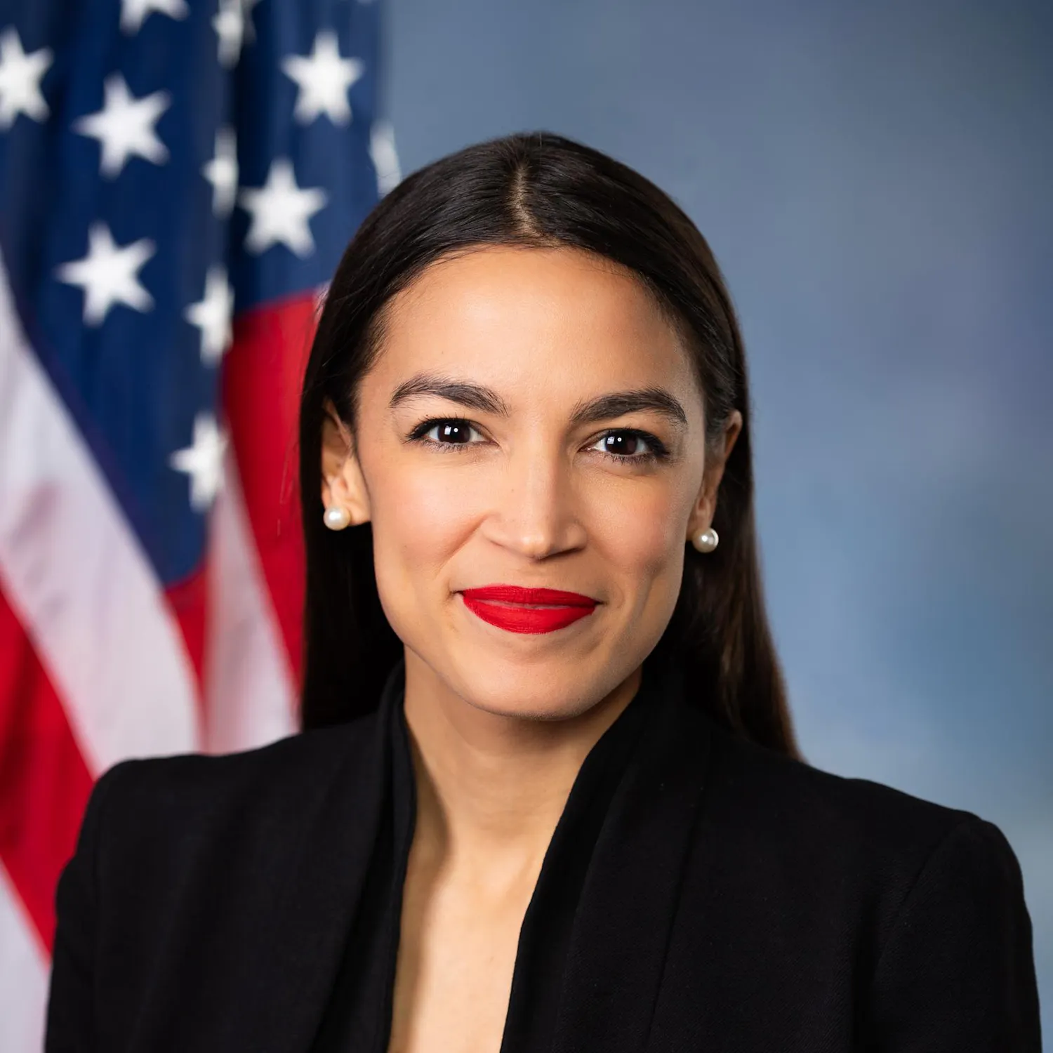 Headshot of Alexandria Ocasio-Cortez with an American flag in the background.