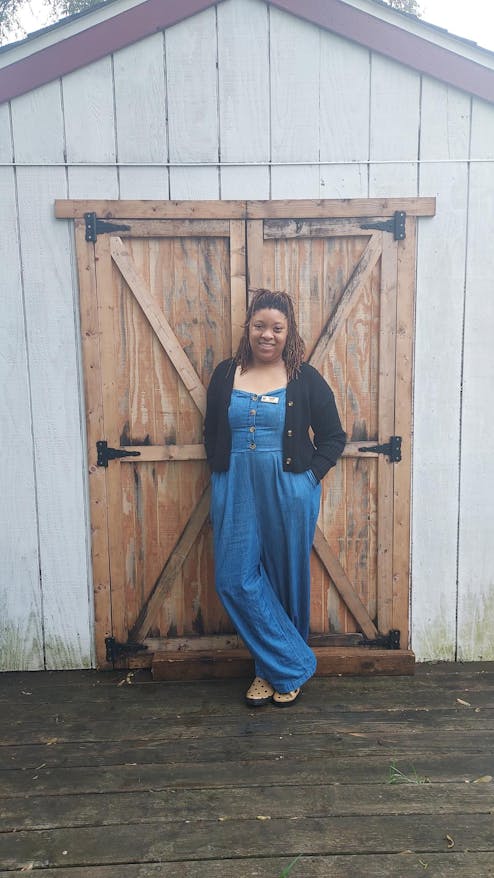 Claire Austin, an organizer at Growing Hope and the manager at the Farmers MarketPlace, stands in front of a wooden door at Growing Hope's headquarters.