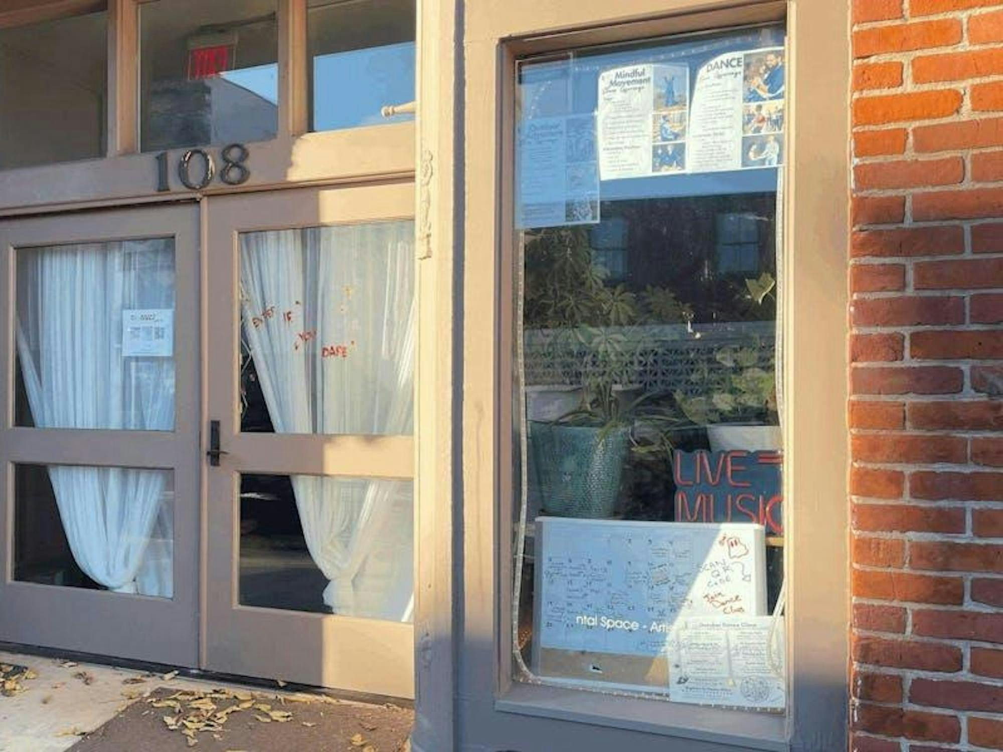 Front facade of Rhizome Roots with plants and posters in the window.